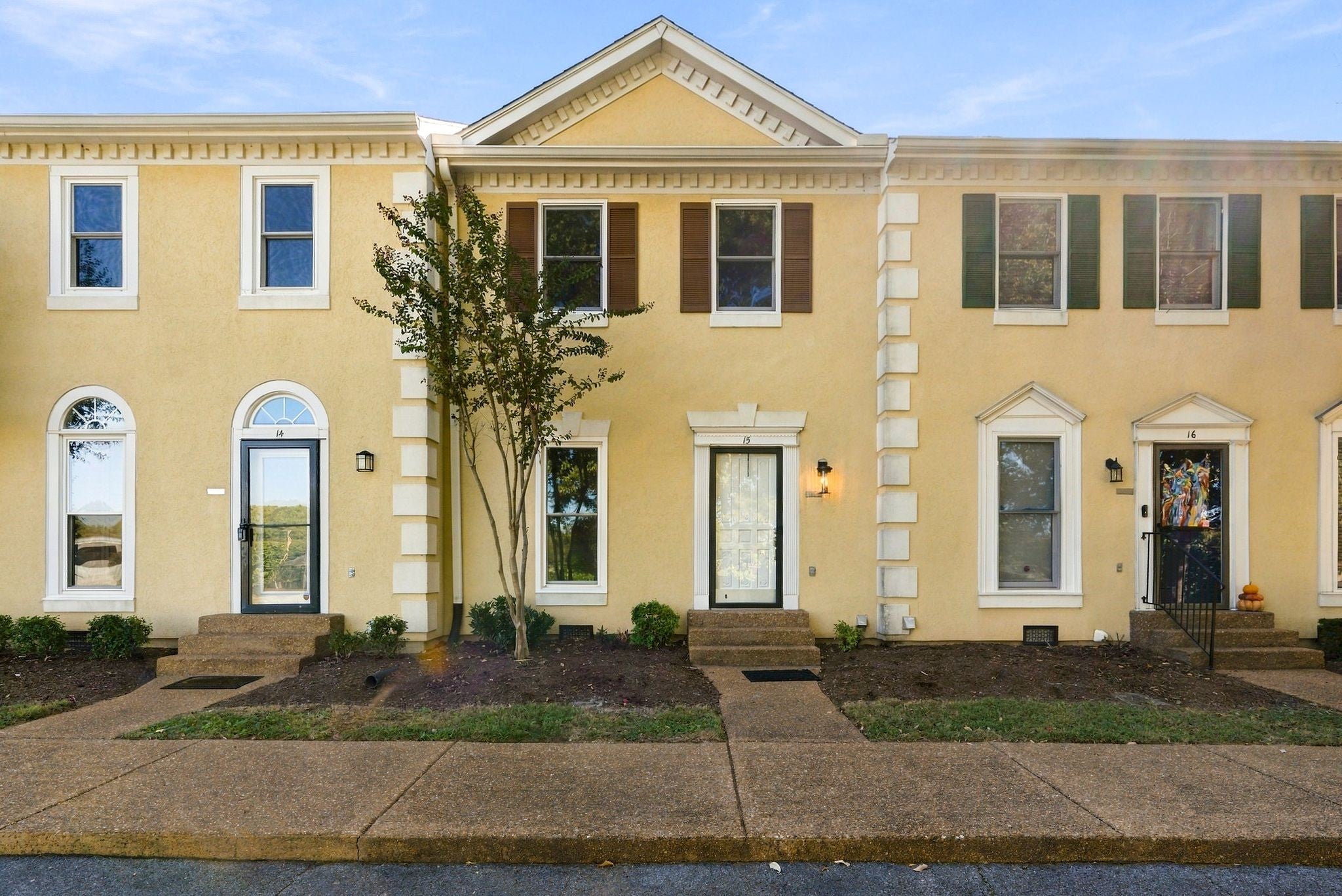 2-bed condo for sale in Franklin, TN 37064, 609 Boyd Mill Ave 15 Row of attached townhomes with yellow stucco facades, dark shutters and small front walkways