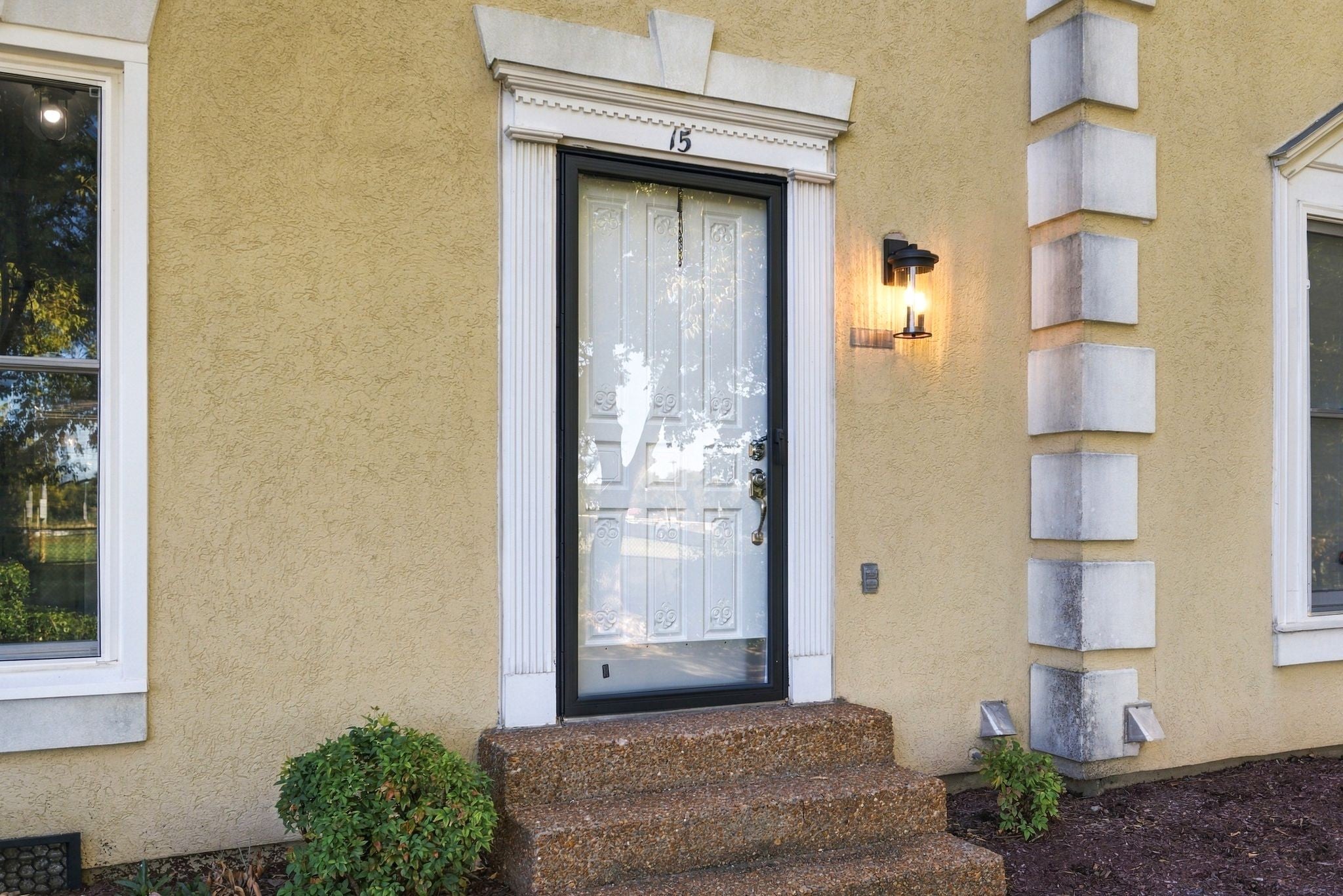 2-bed condo for sale in Franklin, TN 37064, 609 Boyd Mill Ave 15 Front door with black frame and glass panels beneath a wall lantern, set in stucco with white decorative surround