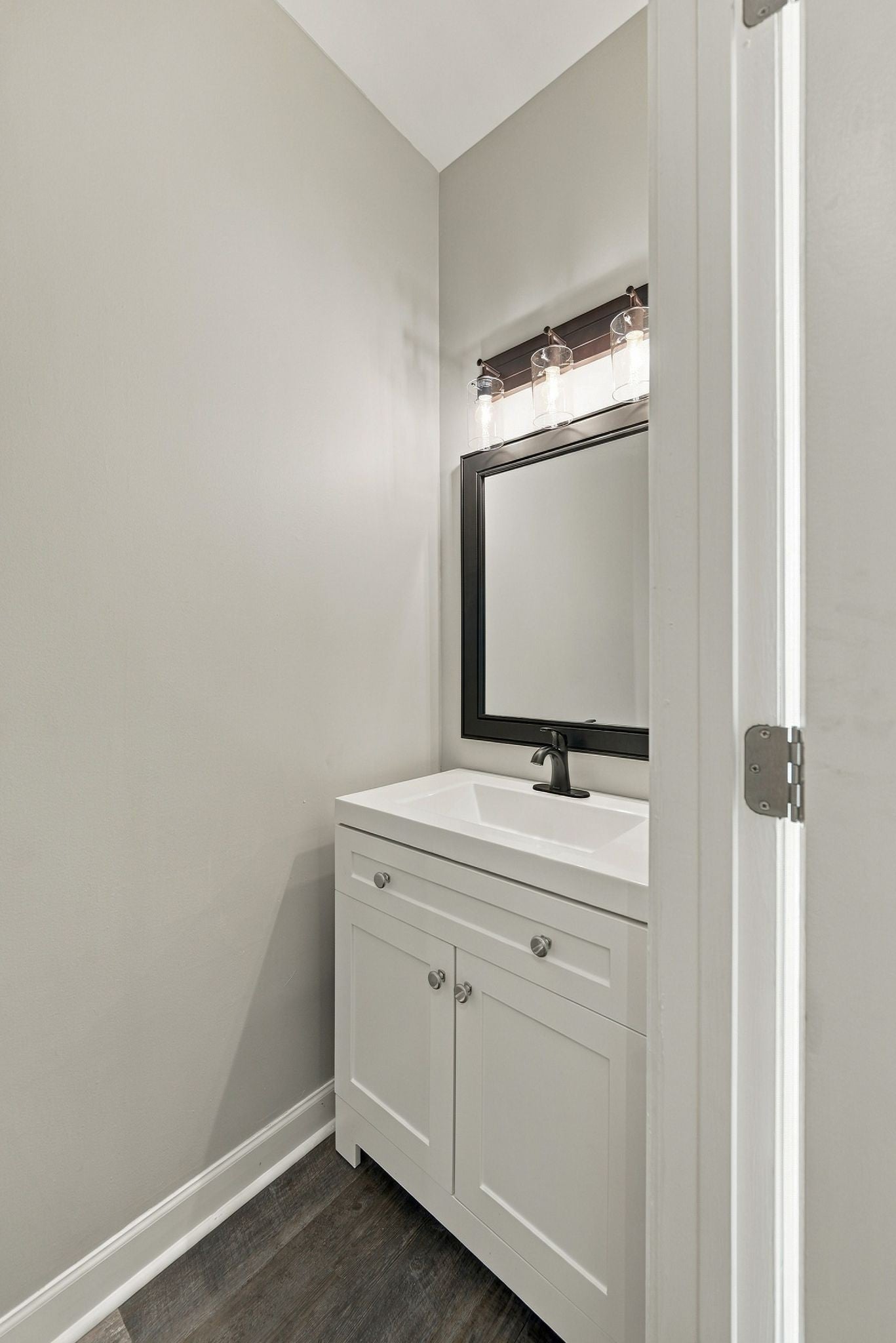 2-bed condo for sale in Franklin, TN 37064, 609 Boyd Mill Ave 15 Half bathroom with white vanity, black framed mirror, glass wall lights and dark wood-look flooring