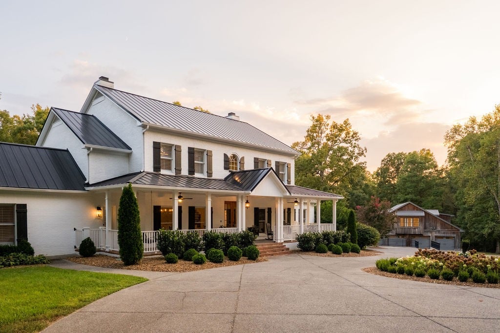 6-bed home for sale in Franklin, TN 37064, 5813 Bending Chestnut Rd Two-story home at 5813 Bending Chestnut Rd, Franklin, TN 37064, with white brick walls, a metal roof and a covered front porch at dusk