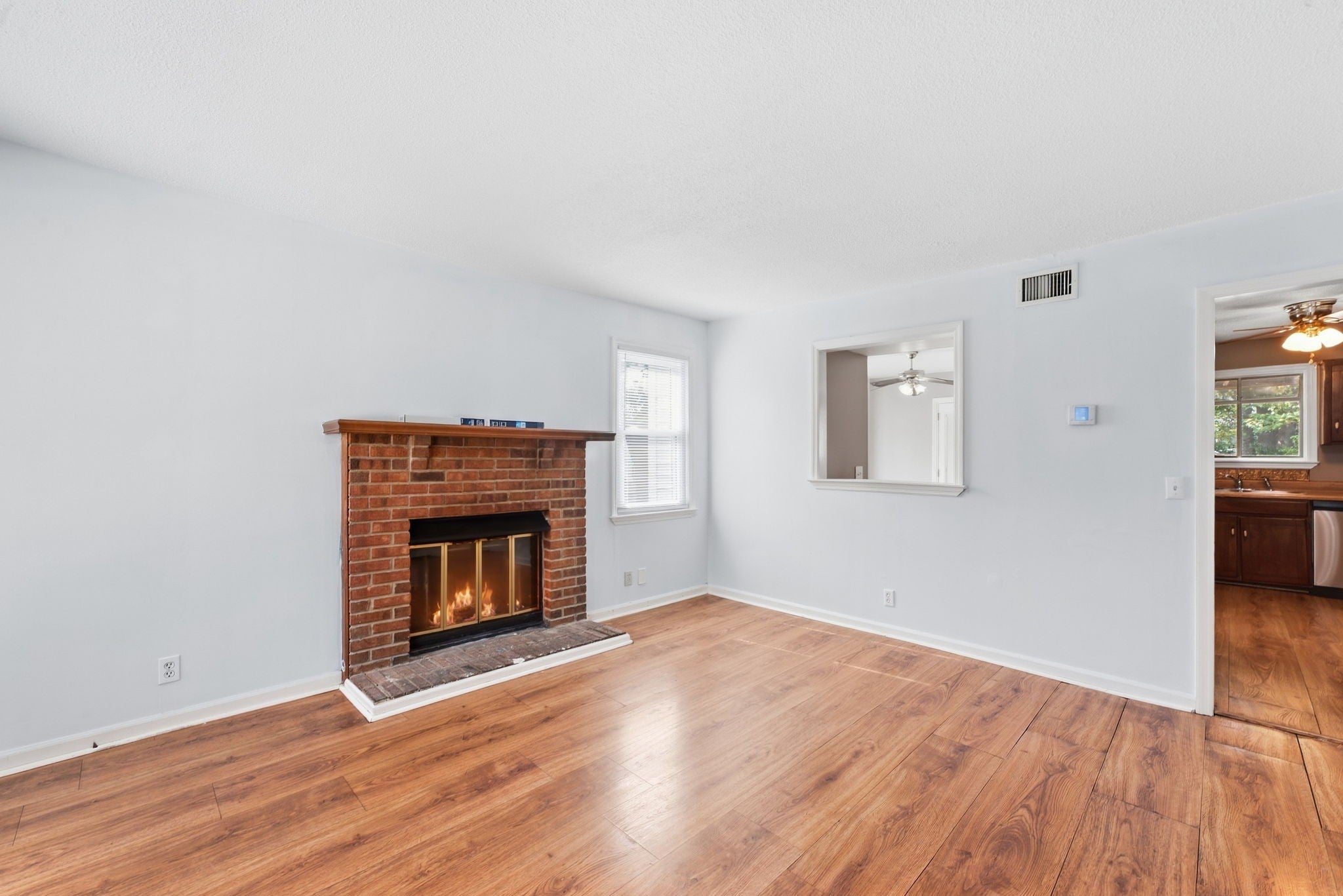 2-bed condo for sale in Antioch, TN 37013, 3379 Oak Trees Ct Living room with wood-look laminate floors, a brick fireplace with a wood mantel and a view into the kitchen