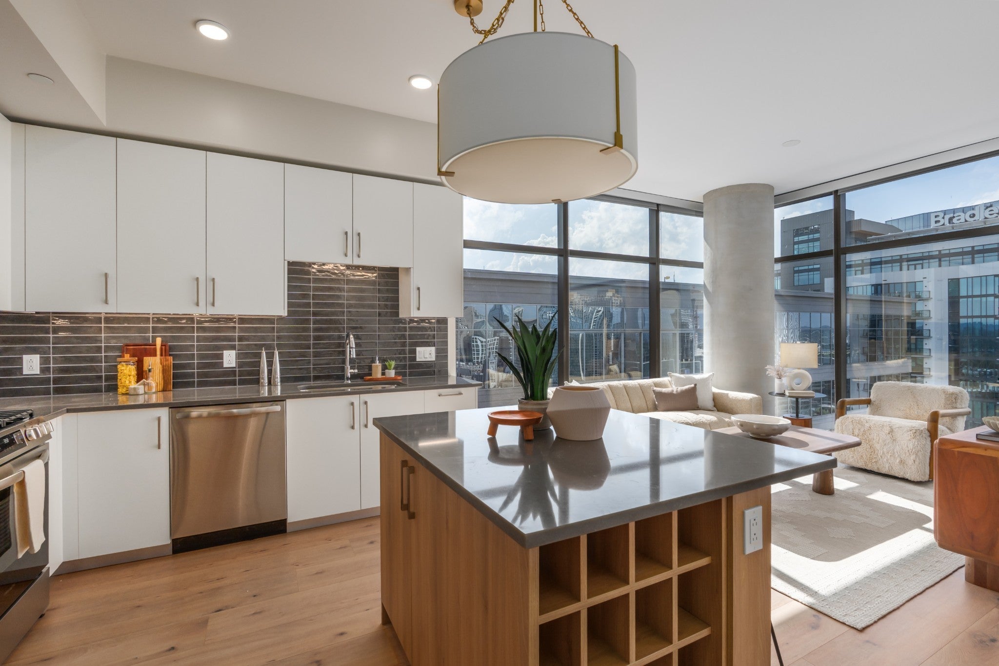 Kitchen island with open wine storage facing the living room and window wall beyond