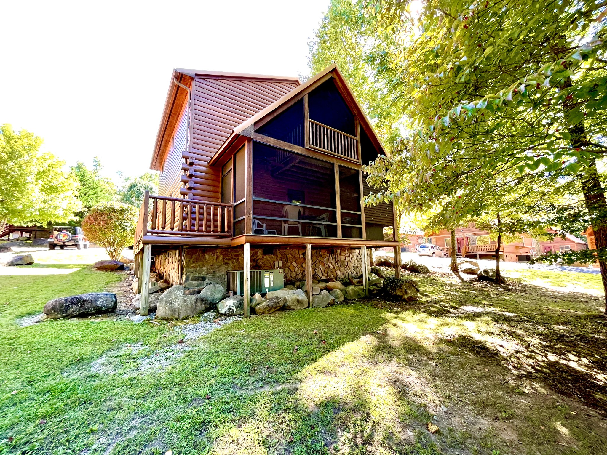 Back view of cabin. Screened in deck w/hot tub. Above deck is the private balcony. The deck from the side of the cabin, wraps around to the screened deck (this allows privacy for downstairs Master Bedroom).