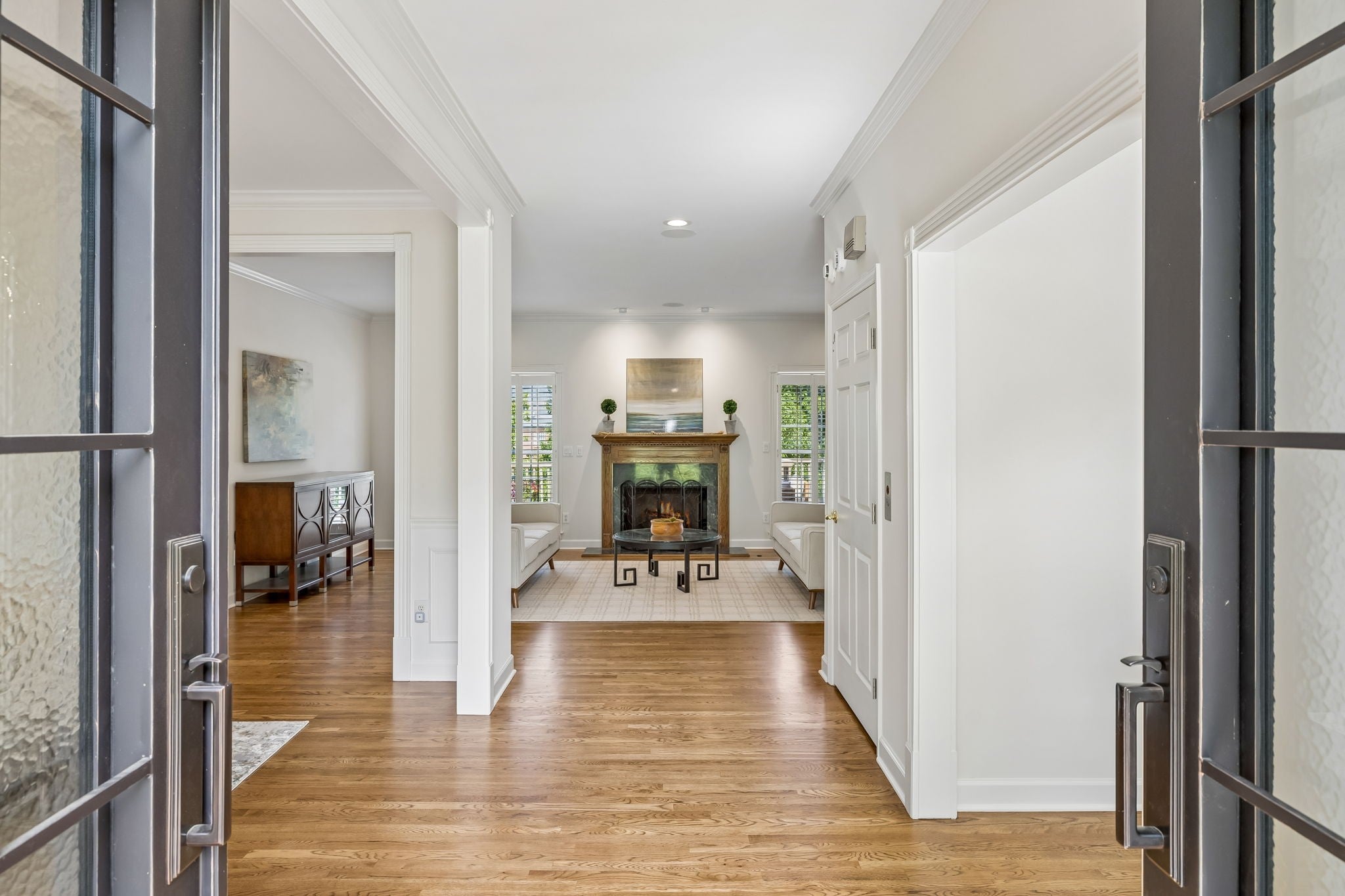 4-bed home for sale in Brentwood, TN 37027, 1521 Puryear Pl Hallway with wood floors view into a living room with a fireplace, built-in mantel and white trim