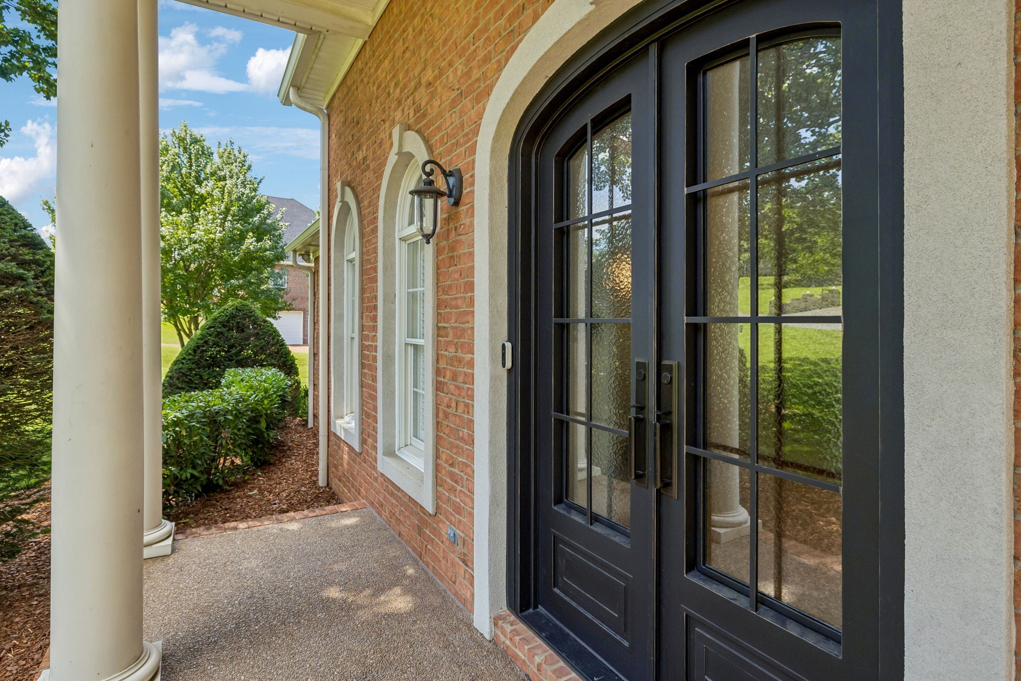 4-bed home for sale in Brentwood, TN 37027, 1521 Puryear Pl Dark double arched front doors with divided glass panes beside brick walls and a white stone surround