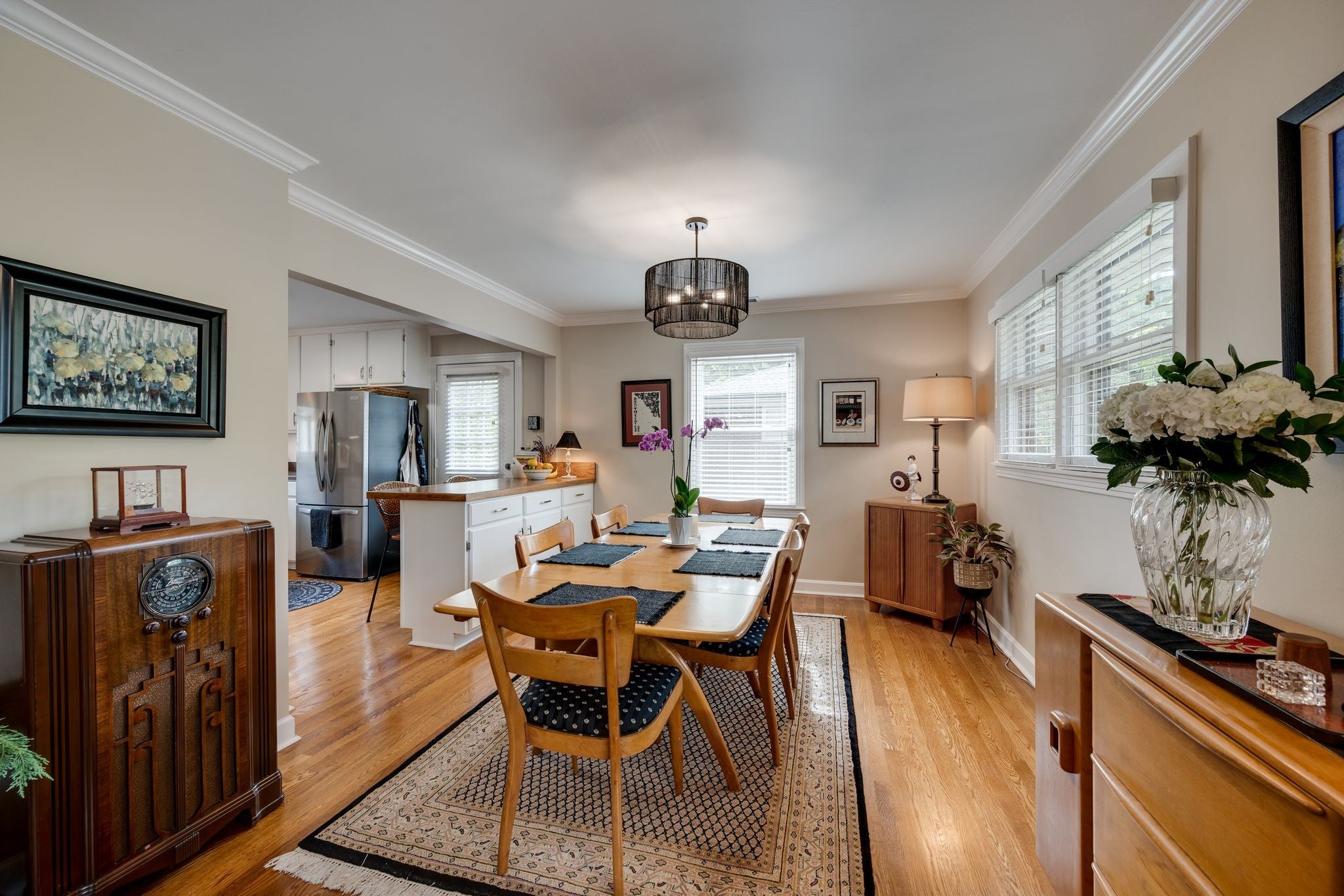 Dining room with wood floors, a pendant light over a wood table and an opening into the kitchen