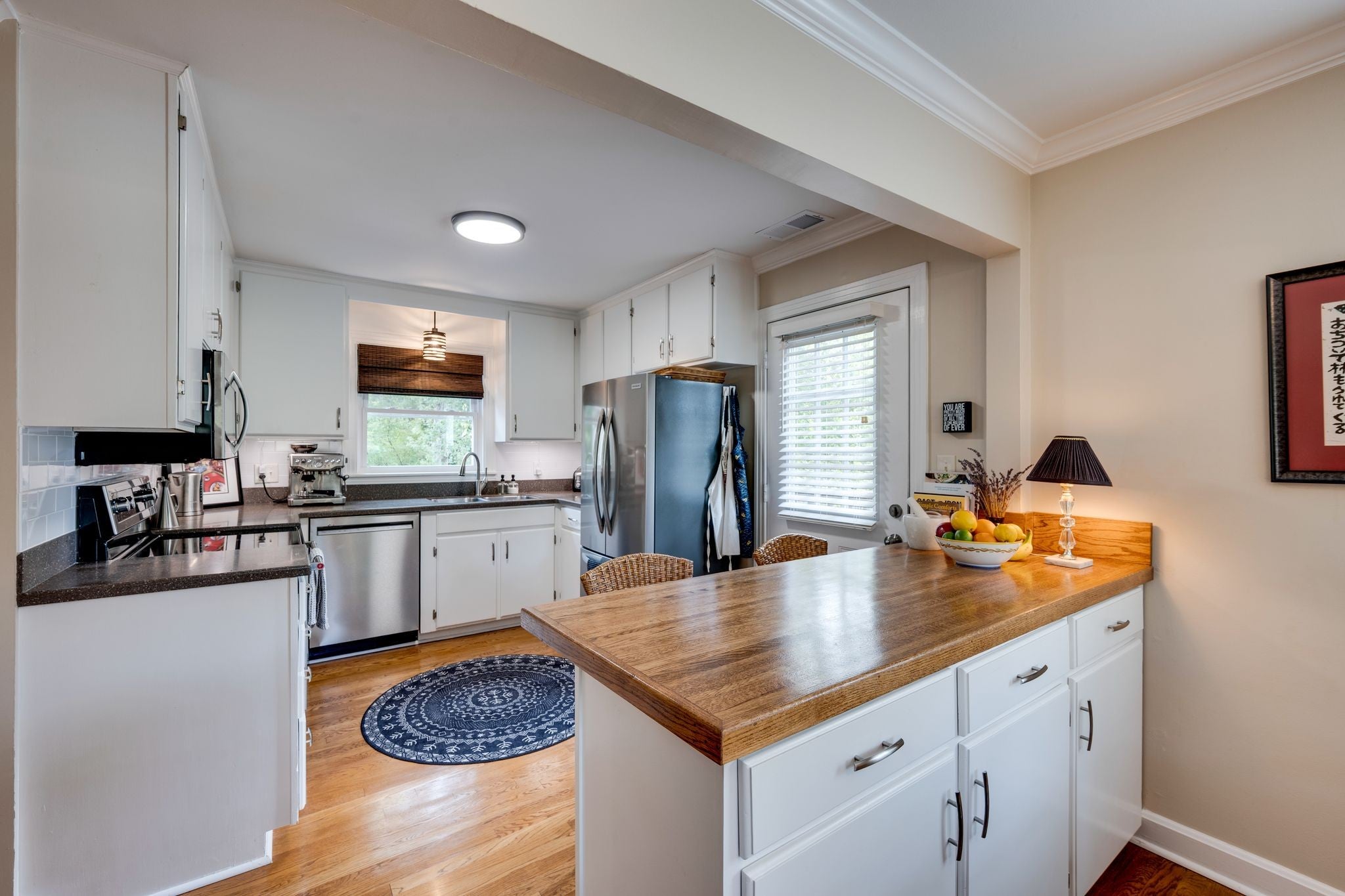 Kitchen with white cabinets, stainless appliances, a wood-top island and a window over the sink