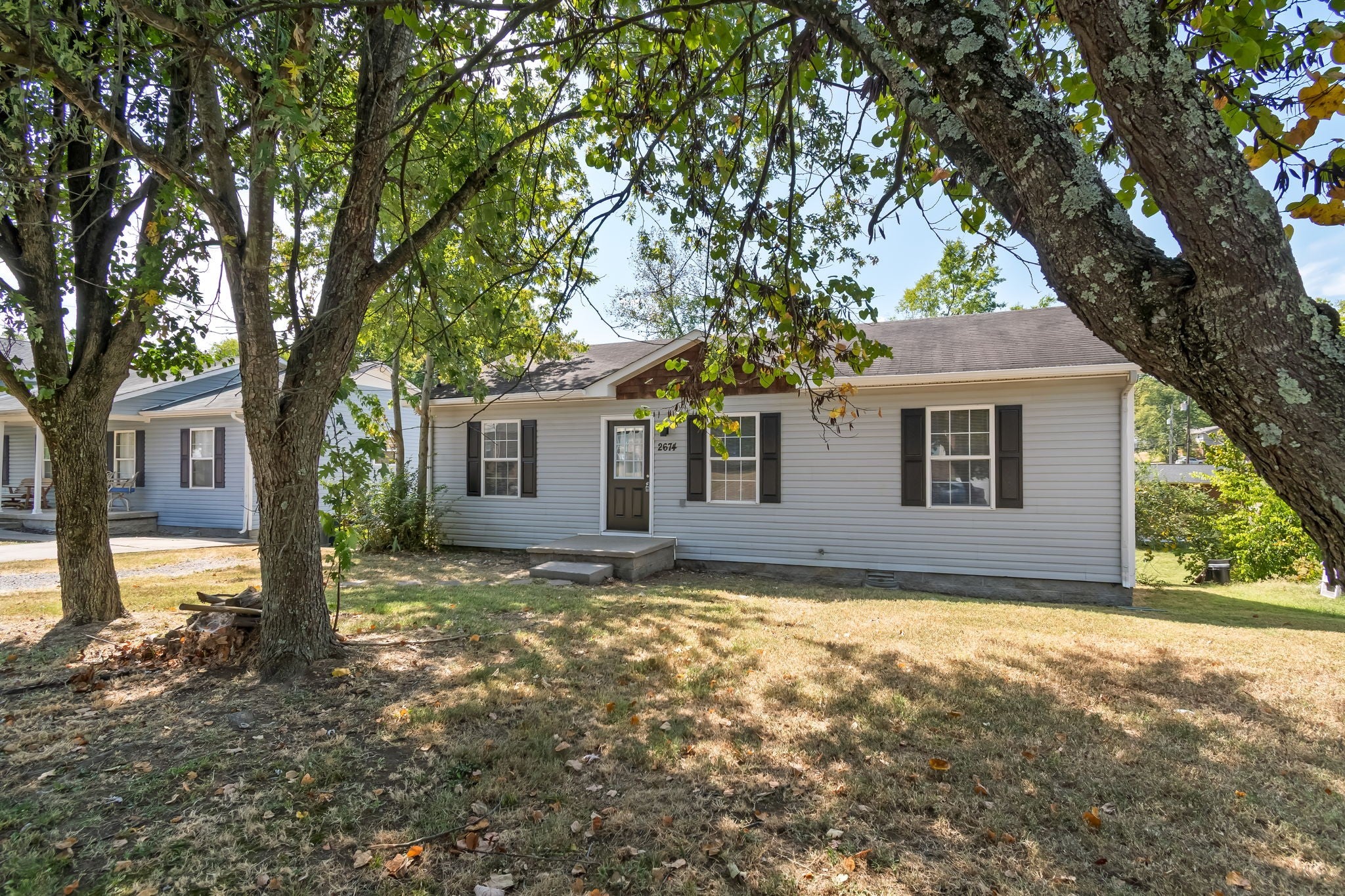 3-bed home for sale in Nashville, TN 37207, 2674 Old Matthews Rd Side view of the single-story house with white siding and a large shade tree shading the front lawn