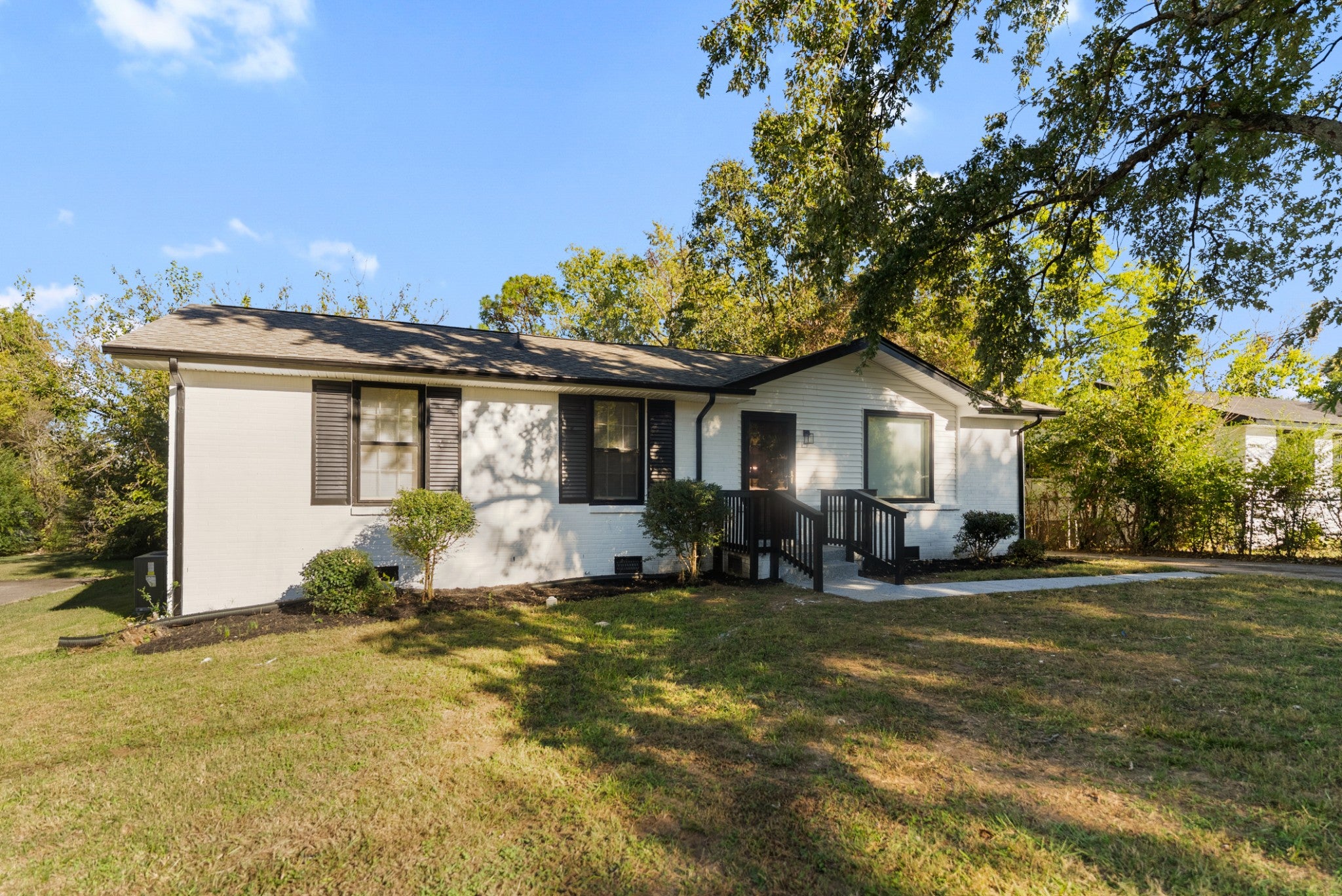 3-bed home for sale in Nashville, TN 37218, 4122 Boyd Dr Side view of a one-story white brick home with dark shutters, a front entry with dark railings and a concrete walkway
