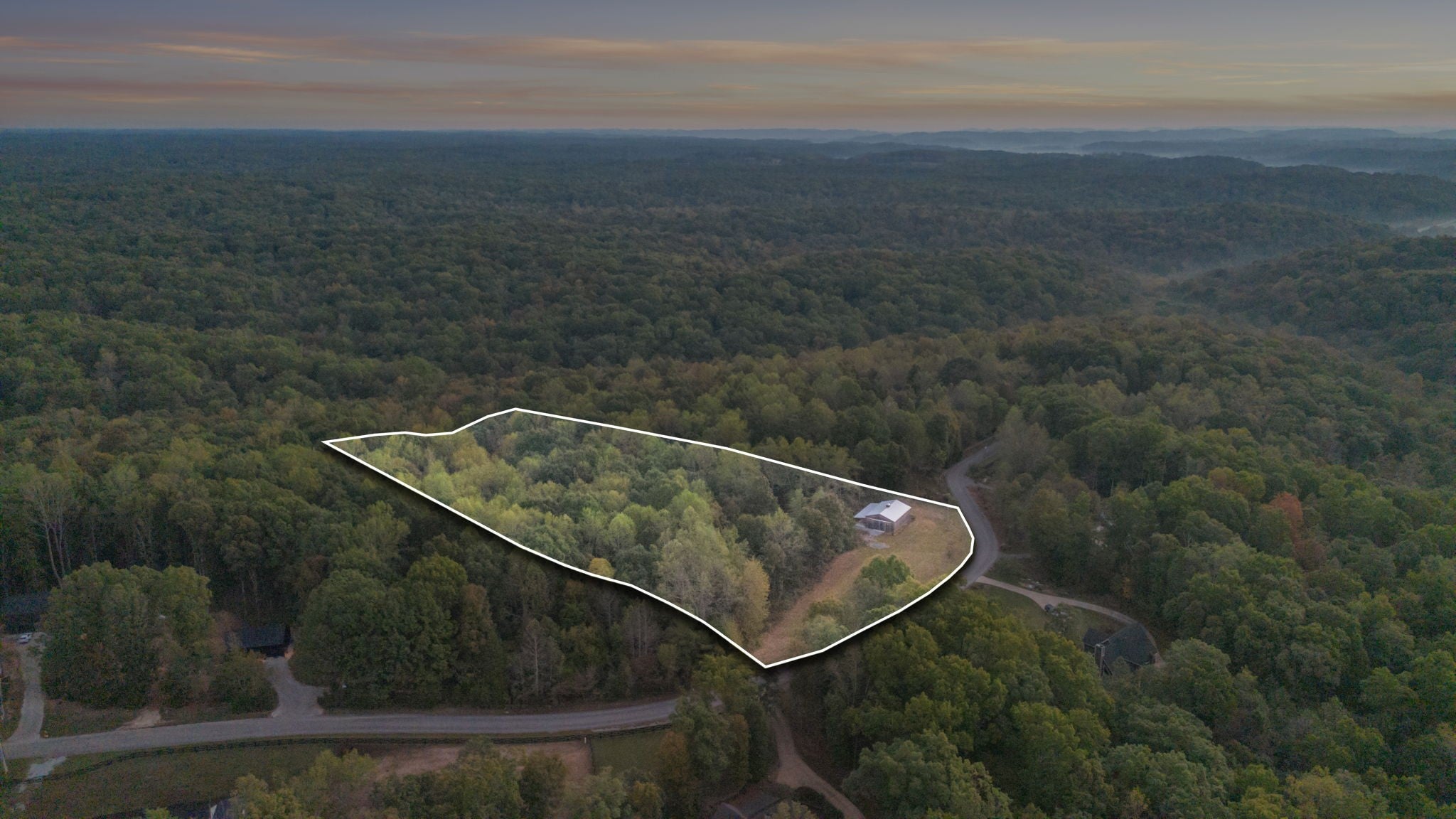 Aerial view outlining the property boundary, with a barn on a cleared area bordered by trees