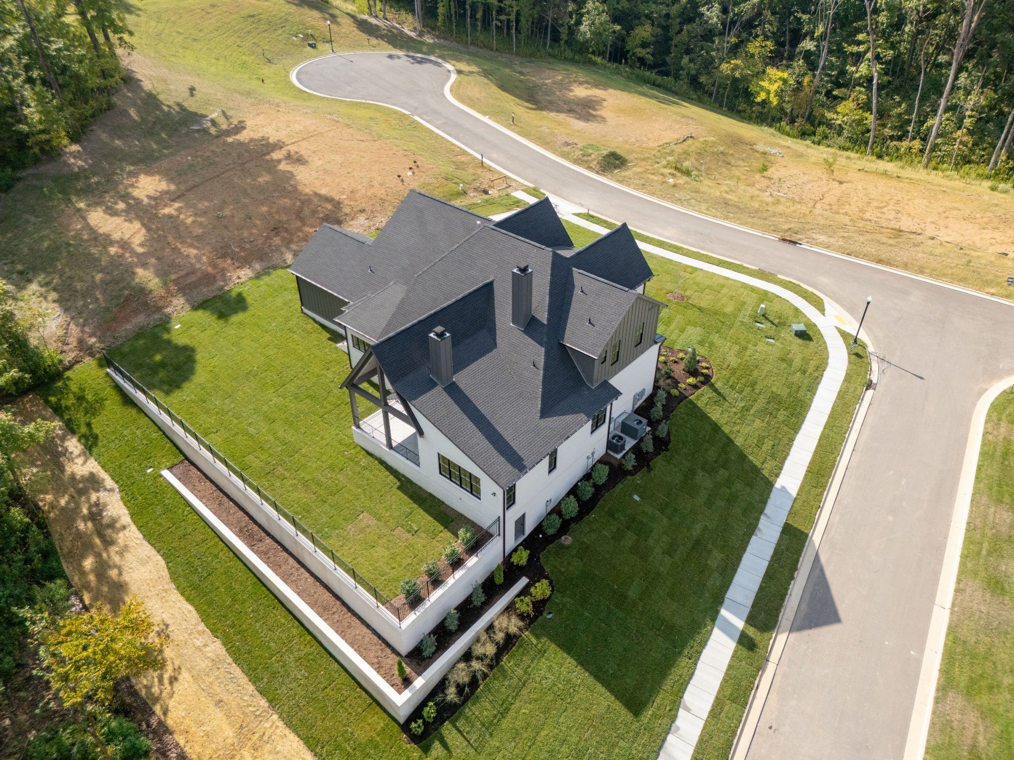 5-bed home for sale in Brentwood, TN 37027, 9405 Dewaal Ridge Aerial view of a two-story home with a dark roof, a covered porch on the side and a white fence along the lot edge