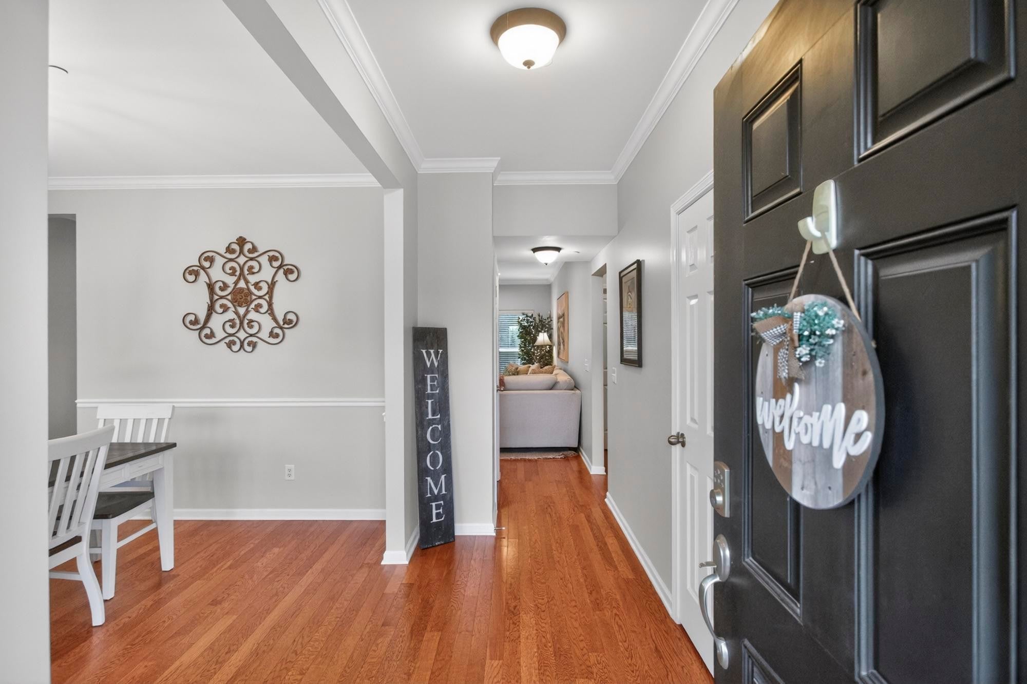 4-bed home for sale in Nolensville, TN 37135, 4713 Jobe Trl Entry foyer with wood floors, crown molding, a black front door and an open doorway into the dining area