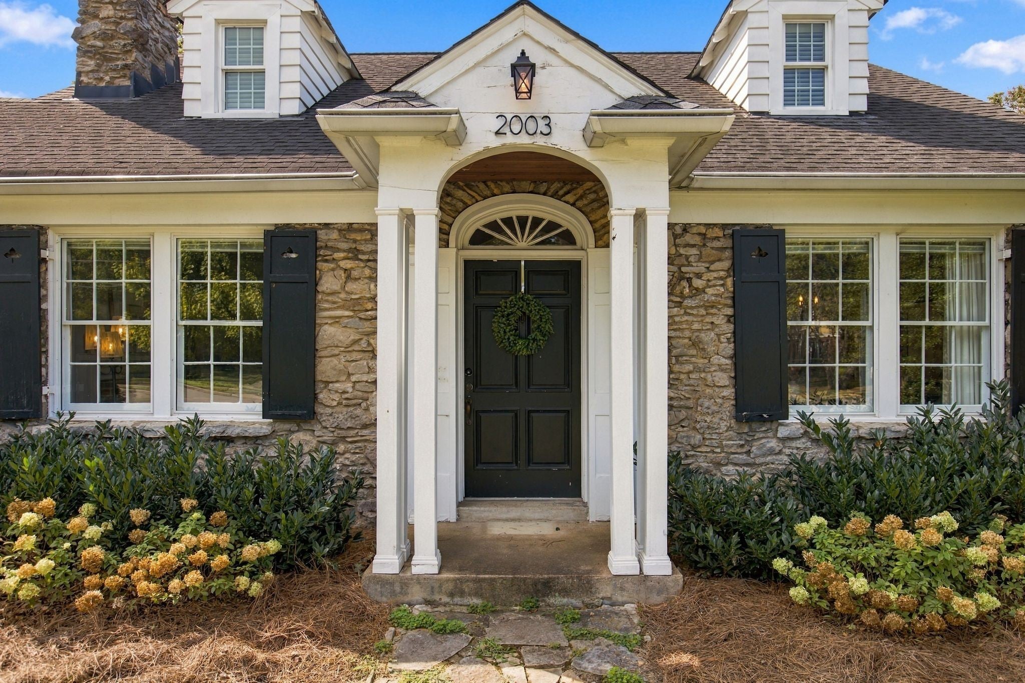 4-bed home for sale in Nashville, TN 37212, 2003 Sweetbriar Ave Arched front entry with white columns, a dark wood door, a fanlight window and stone walls beside shrubs