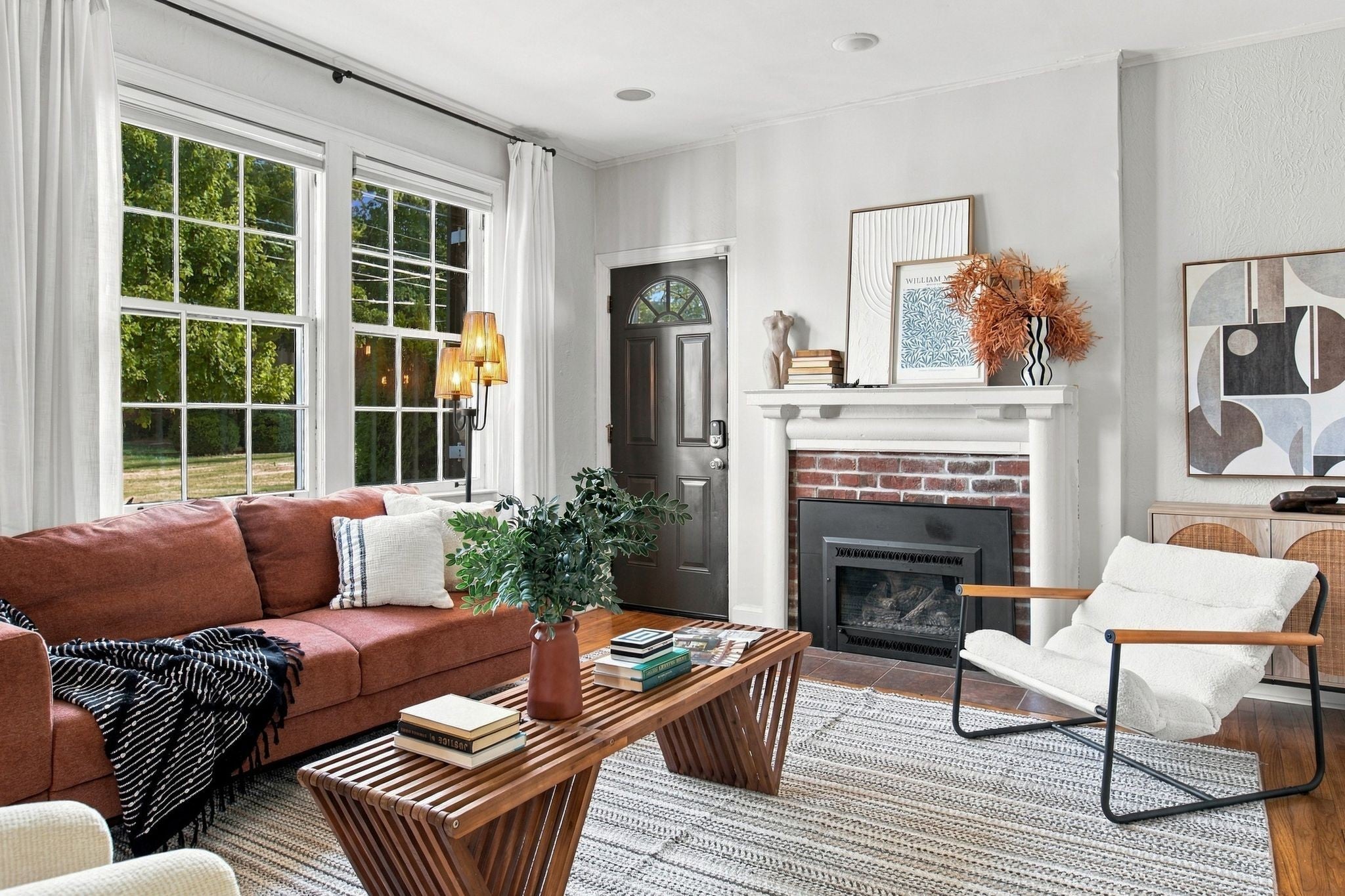 4-bed home for sale in Nashville, TN 37212, 2003 Sweetbriar Ave Living room with a sofa, a brick fireplace with a white mantel, wood floors and tall windows with white curtains