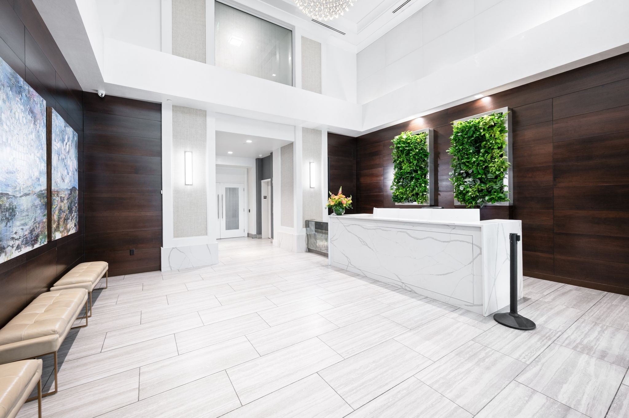 Lobby reception desk with a veined white stone top, green wall panels and light wood paneling