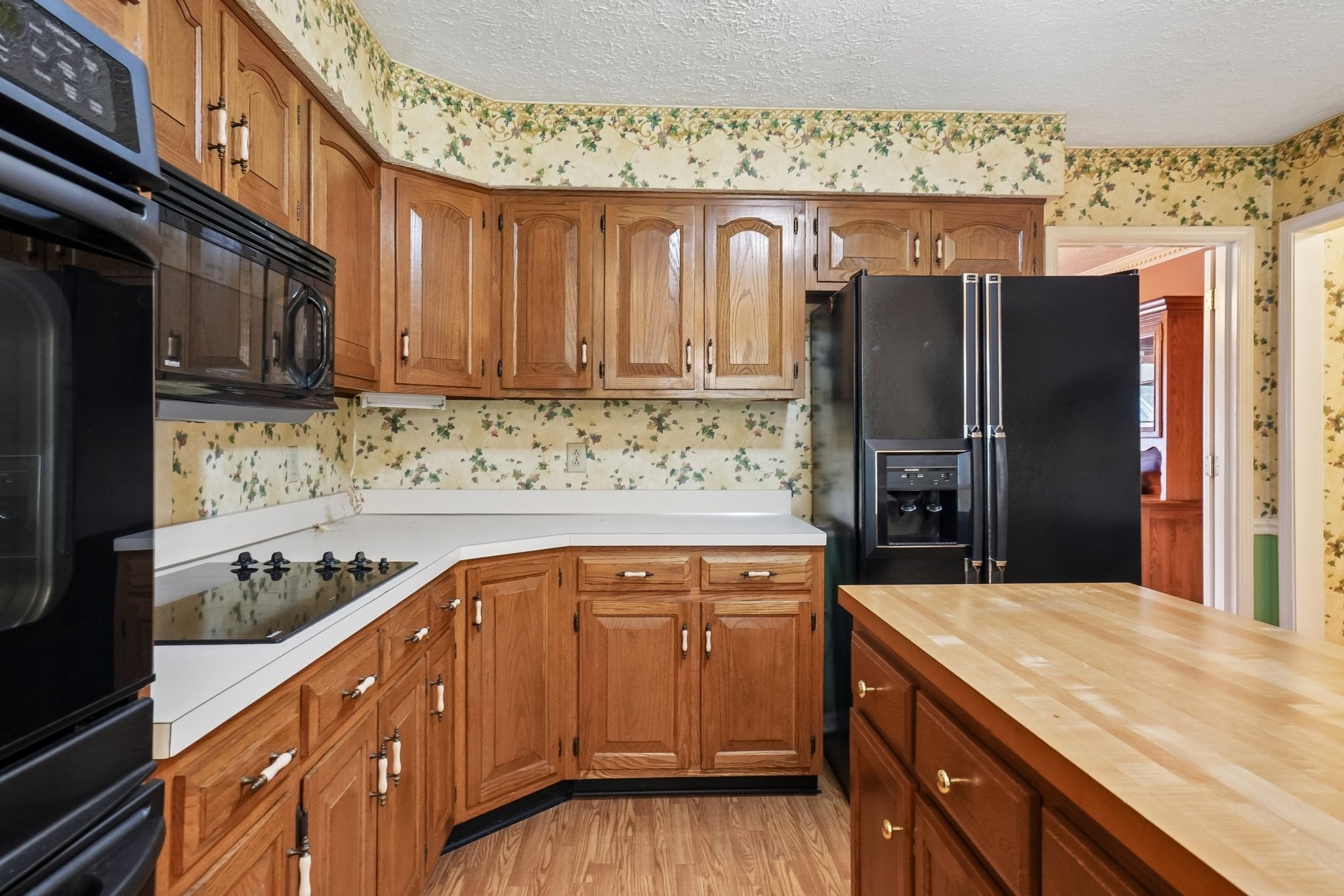 3-bed home for sale in Antioch, TN 37013, 3921 Hillshire Dr Kitchen with honey-toned wood cabinets, black appliances, a cooktop in a light countertop and a wood-top island