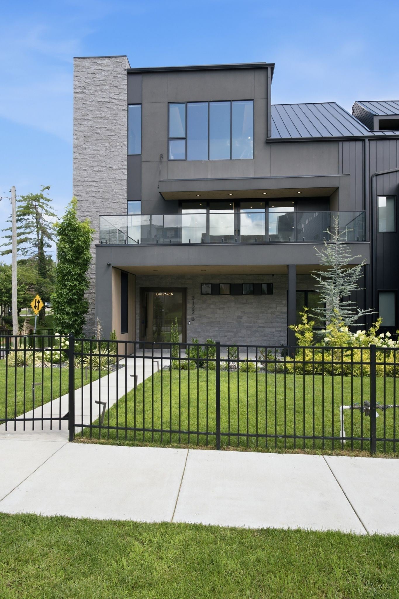 4-bed condo for sale in Nashville, TN 37203, 3122b Belwood St Townhouse entry with a covered balcony, stone wall, shrubs along the walk and a black metal fence