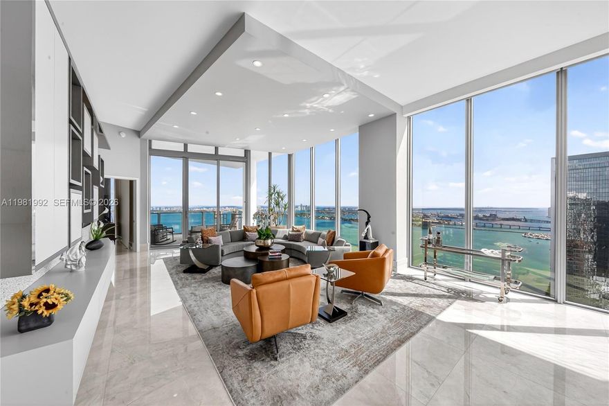 Experience elevated waterfront living in this spectacular 5-bedroom, 5.5-bath residence with a spacious den on the 49th floor at Biscayne Beach, offered at $5,350,000. This designer-finished home features soaring 12-foot ceilings and dramatic floor-to-ceiling windows that frame breathtaking bay and city views while filling the interiors with natural light.
A grand open living and dining area creates an impressive setting for entertaining as well as comfortable everyday living. The chef’s kitchen is anchored by a striking onyx waterfall island, blending sculptural elegance with functionality.
The thoughtfully designed layout includes two luxurious primary suites, each with spa-inspired bathrooms and double vanities, along with three additional bedrooms and a large den ideal for a media room, office, or lounge.
Enjoy seamless indoor-outdoor living with two expansive private terraces, one featuring a summer kitchen perfect for alfresco dining while taking in panoramic Biscayne Bay views.
Additional features include electric blinds throughout with sheer and blackout shades, central air conditioning, and a separate laundry room. Offered fully designer-furnished and turnkey—simply bring your toothbrush and move right in.
A rare opportunity to own a luxury sky residence in one of Edgewater’s premier waterfront buildings.