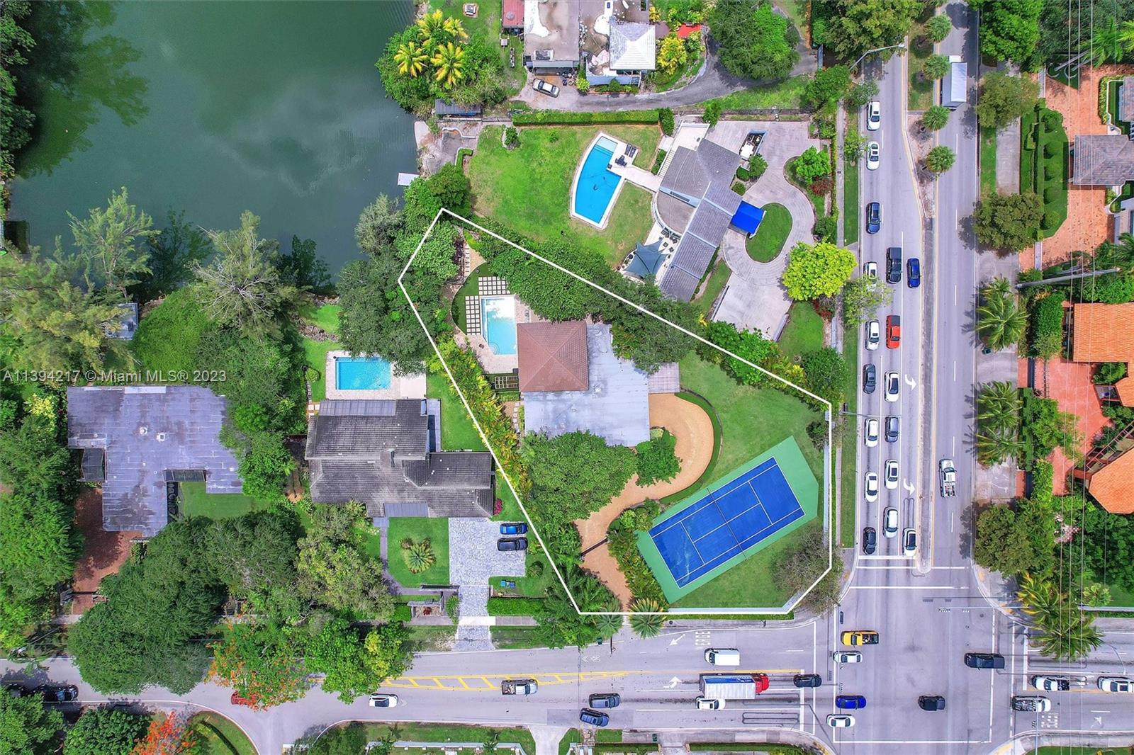 An exquisite fully gated & walled corner estate occupies nearly 1-acre of serene beauty. Enjoy a tennis court, a tranquil lake with an elevated dock, & a double infinity edge pool, all embraced by stunning mature trees. With a captivating stone facade at the entry & fireplace, this home exudes a timeless charm inspired by Frank Lloyd Wright. Featuring a study loft & a game room, every space is designed for comfort. Large windows offer breathtaking lake views, while a summer kitchen with BBQ, sink, & fridge invites you to entertain. Relax on the expansive covered terrace or embrace the outdoors in the playground. The property boasts a new roof (2020), updated bathrooms (2019), & numerous updates in 2012. With its superb location, this home combines elegance & convenience seamlessly.