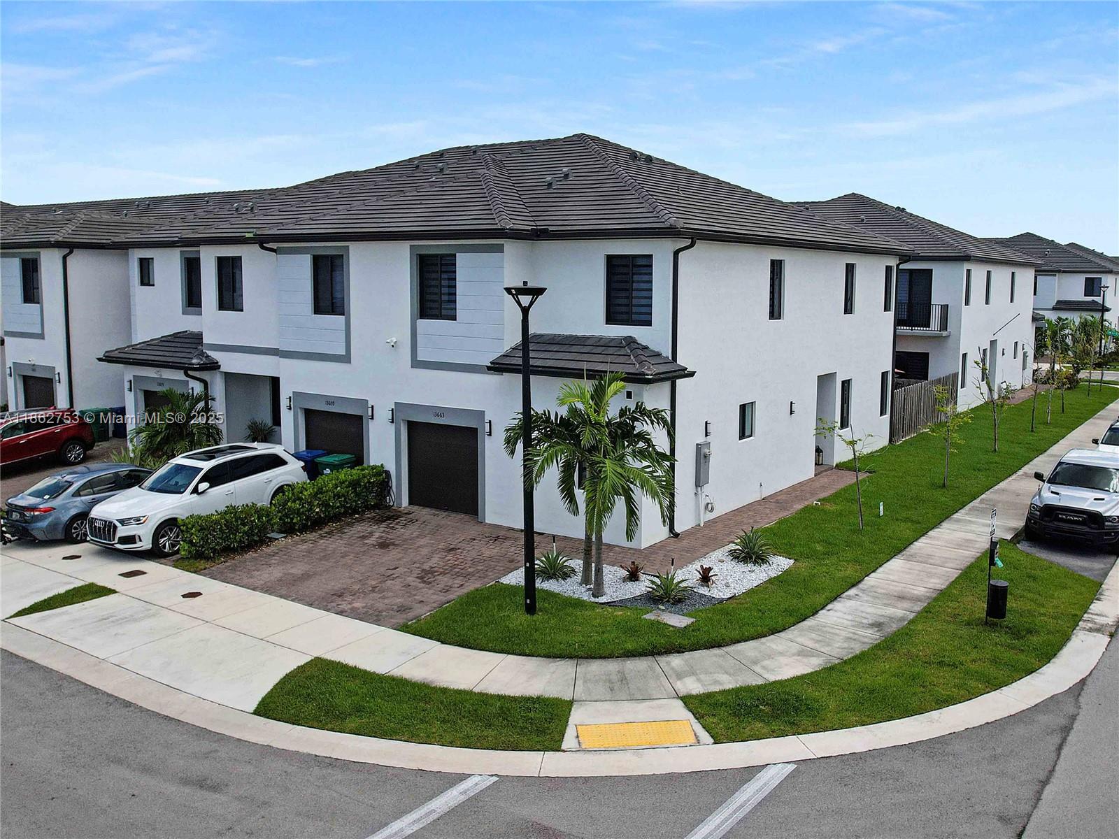 Like-new, spacious corner townhome in Century Gardens South. Built in 2023, it features 24” x 24” porcelain tile floors downstairs, laminate upstairs, European-style cabinetry, quartz countertops with matching backsplash, impact windows and doors, upgraded staircase railings, and exterior lighting. With six extra windows, this rare corner unit lives like a single-family home enjoying ample natural light. The floor plan includes one bedroom with en-suite bath on the ground level, ideal for guests or multigenerational living. Upstairs, the generous primary suite is joined by two additional bedrooms, a full bath, and laundry area. The fenced backyard is perfect for entertaining with a new paver patio, pergola, and low-maintenance turf. Low HOA and convenient location just west of Kendall.