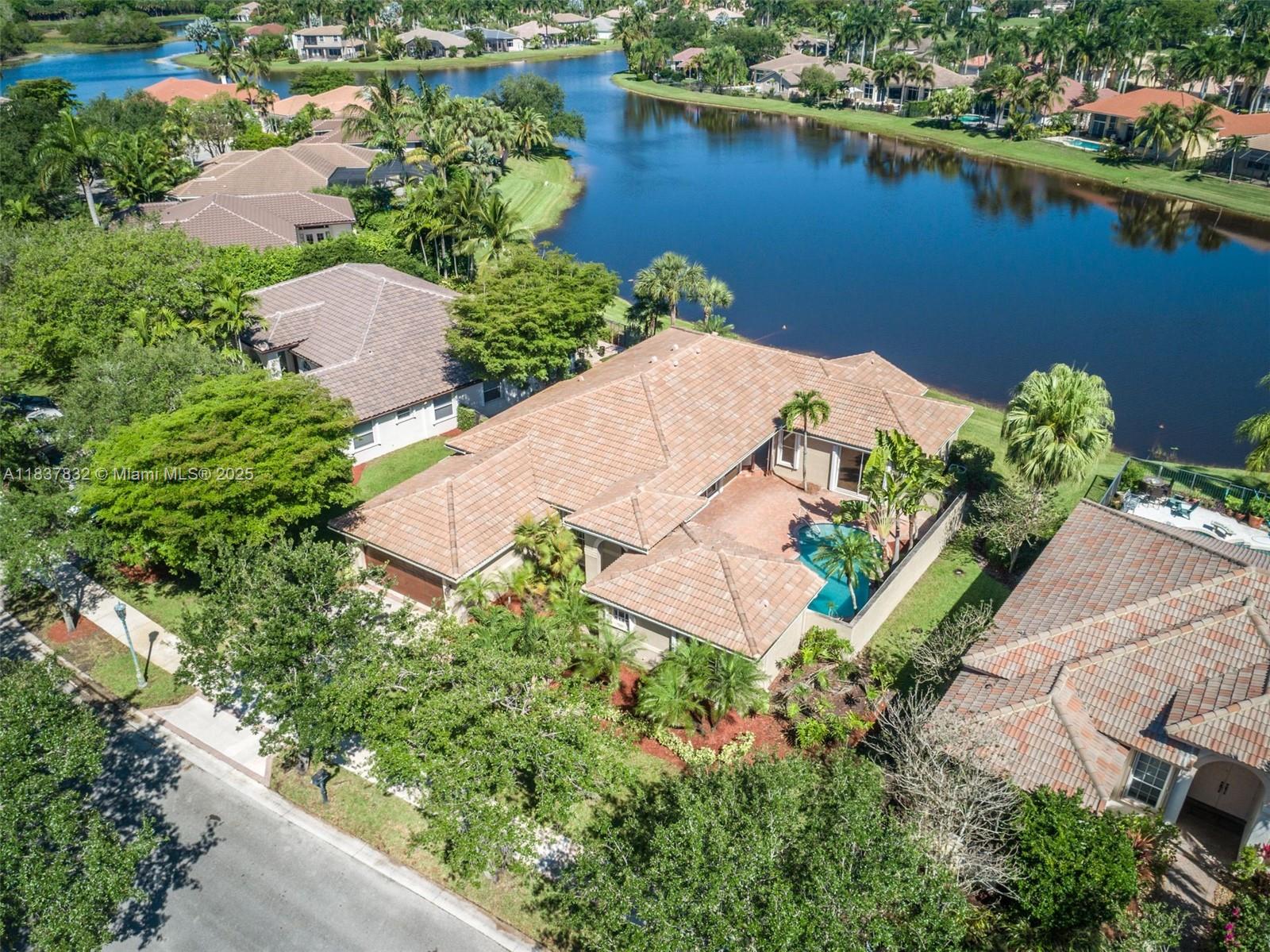 Beautifully renovated courtyard model in the exclusive gated community of Weston Hills. This home features a modern open floor plan, white kitchen cabinets, stainless steel appliances, and contemporary bathrooms with frameless glass showers. The primary bath includes a luxurious stand-alone soaking tub. Wood floors in living areas, porcelain in baths. Main house offers 3 spacious bedrooms and 2 full baths. Separate in-law suite with pool view—perfect for guests or office. Enjoy stunning lake views. Roof (2015), A/C units (2014 & 2016), newer water heater, and full accordion shutters. Move-in ready!