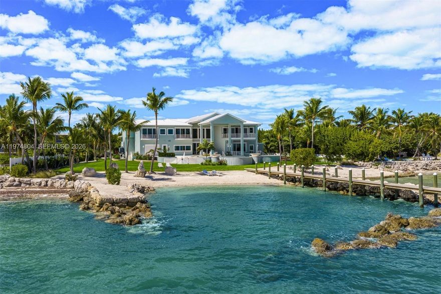 Newly completed in 2025, this exceptional oceanfront estate is located in the heart of The Florida Keys on the premier ocean side of Islamorada. A gated entry welcomes you through lush tropical landscaping and a diverse fruit-tree grove, setting a private and refined arrival. Set on over 2 usable acres with 210 feet of private sandy beachfront and a protected cove, the residence spans 7,590 square feet of interior living space & 1,736 square feet of exterior living, with an expansive 230-foot dock. Designed for seamless indoor-outdoor living, the home features a dramatic great room with 23-foot ceilings, panoramic Atlantic exposure, and expansive covered terraces with summer kitchen and outdoor dining areas. A 65-foot heated lagoon-style pool with swim-up bar and fire-pit lounge creates a resort-caliber setting. The chef’s kitchen is appointed with Sub-Zero, Wolf, and Thermador appliances. Additional highlights include dual primary suites, private orchid garden, lounge & recreation room, elevator, Sonos surround sound, impact windows and doors, metal roof, double-height garage, water-sports storage room and a full home generator. The essence of beachfront living in Islamorada, combining impressive scale and ultimate privacy. ***A contiguous 0.7-acre lot with development rights for an ancillary building with upstairs storage is available separately.