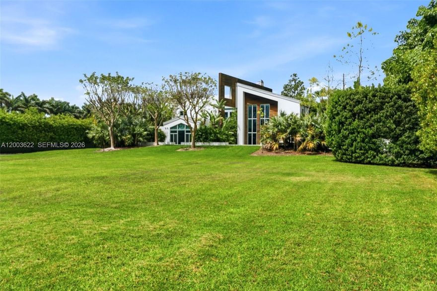Experience unparalleled modern luxury in this spectacular split plan 6,355-square-foot architectural masterpiece set on a sprawling 2.46-acre private estate in Redland. Designed for the most discerning buyer, this stunning compound features a main residence and secondary structures seamlessly connected by elegant breezeways and lush tropical landscaping. The striking contemporary facade, characterized by crisp white lines, natural wood accents, and expansive oversized windows, sets the tone for the exceptional design found throughout. 

Step inside to discover a breathtaking two-story great room anchored by a dramatic floor-to-ceiling concrete fireplace and an open-tread floating staircase with sleek cable railing. The open floor plan is bathed in natural light, highlighting the high ceilings, modern pendant lighting, and premium finishes. Entertain effortlessly in the custom industrial-chic bar area, complete with a live-edge wood counter, or utilize the dedicated professional production studio space, perfect for creatives or home-based businesses. 

The outdoor living spaces rival a five-star resort. A pristine geometric swimming pool is surrounded by manicured turf and stepping-stone pathways, leading to a massive thatched-roof tiki pavilion equipped with built-in seating and an outdoor television. Multiple covered terraces, two second-floor balconies overlooking the grounds, and a magnificent paver courtyard driveway complete this extraordinary offering.