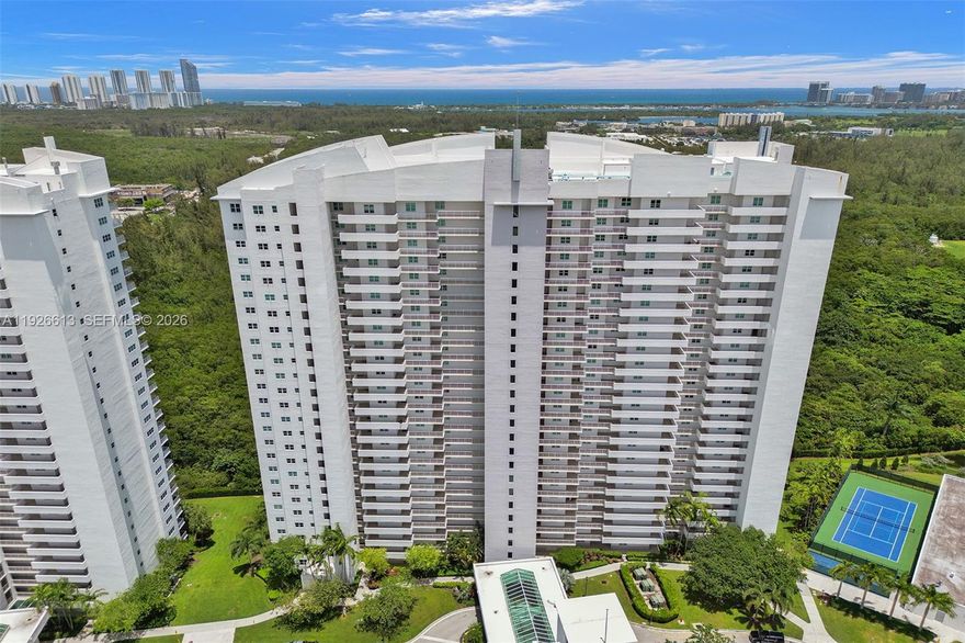 Rarely available penthouse corner residence offered for sale by its original owners! This spacious 2-bedroom, 2-bath plus den features soaring 12-ft ceilings and expansive skyline views of Sunny Isles Beach, Haulover, and Bay Harbor Islands. The layout feels grand and filled with natural light. Stone floors have just been polished, and both bedrooms feature brand-new Chevron-style engineered herringbone wood flooring. Dishwasher, microwave, and stovetop are brand new. This is the only line in the building with no windows facing the catwalk, offering enhanced privacy and additional windows, including a windowed foyer, all bathrooms, and extra windows in the primary bedroom. Thick hurricane-impact windows provide excellent sound insulation. Assigned covered parking conveniently located on the first level, with the option to rent a second space. A must-see penthouse. Building amenities include pool, gym, tennis court, playground, dog wash station, and high-speed internet/cable. Conveniently located near Costco, Target, Publix, new Mater Academy, UM Health, Pura Vida, Reserve Padel, and the beaches.