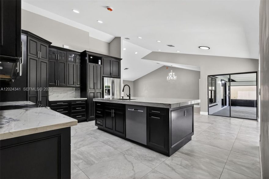 Beautifully updated 4-bedroom, 2-bath single-family home in Boynton Beach featuring a bright open-concept layout, vaulted ceilings, large-format tile flooring, and modern finishes throughout. The spacious living and dining areas flow into a standout kitchen with dark custom cabinetry, stone-style countertops, stainless steel appliances, oversized island, and breakfast bar seating. The split-bedroom layout offers privacy and flexibility, including a primary suite with wood-look flooring, chandelier lighting, screened patio access, a custom walk-in closet, and an updated bath with dual sinks and a glass-enclosed shower. Additional bedrooms feature tile floors, ceiling fans, built-in storage, and generous closet space. Enjoy Florida living with multiple sliding doors leading to a large screened-in patio, open courtyard-style patio, and private fenced backyard with mature landscaping and fruit trees. Additional highlights include a two-car garage, dedicated laundry area, and over 3,900 total square feet.