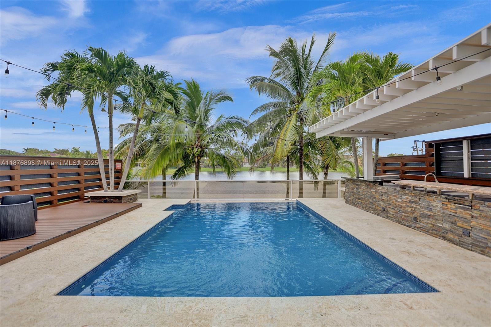 The distinctive qualities of this lakefront pool residence are attributed to its meticulous details. The home features designer finishes throughout including a custom European-style kitchen and artistic lighting fixtures, all masterfully upgraded with contemporary enhancements. The interior is a harmonious blend of eclectic elements, exuding both style and comfort. It is secured by impact windows and doors. The interior spaces transition seamlessly to the outdoor area, which is ideal for leisurely days spent overlooking an impressive heated salt water pool, complete with an outdoor open bar and kitchen, as well as a picturesque lake, perfect for relaxation and entertainment. This property is an exceptional choice for those in search of a unique home that embodies undeniable elegance.