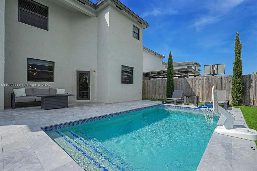 This exceptional 5-bedroom, 3.5-bath home in the desirable Pine Vista community opens to a bright & spacious living & dining area. A welcoming family room overlooks the kitchen, features stainless steel appliances, ample cabinetry, & a generously sized pantry. The property includes three separate entryways & hurricane-impact doors, providing added flexibility, security, & peace of mind. The impressive primary suite is expansive & versatile, offering ample room for a sitting area, home office, or additional furnishings. It also features an oversized closet with custom built-ins. The primary bathroom is well-appointed with a jacuzzi tub, separate shower, and dual vanities. The additional bedrooms are well-proportioned and comfortably sized, providing flexibility for family, guests, or multi-use spaces. A full bathroom on the first floor offers direct access to the outdoor area—ideal for poolside use.Step outside to a private backyard with a sparkling heated pool, inviting lounging area, & an expansive patio with plenty of space to relax and entertain. The two-car garage has been upgraded into a gym featuring top-of-the-line new equipment, while still offering ample storage space.
Additional features include a dedicated laundry room & thoughtfully designed living areas throughout. Residents enjoy resort-style amenities including a modern clubhouse, fitness center, & community pool.
Don’t miss this opportunity to own a beautifully designed home in a sought-after community!