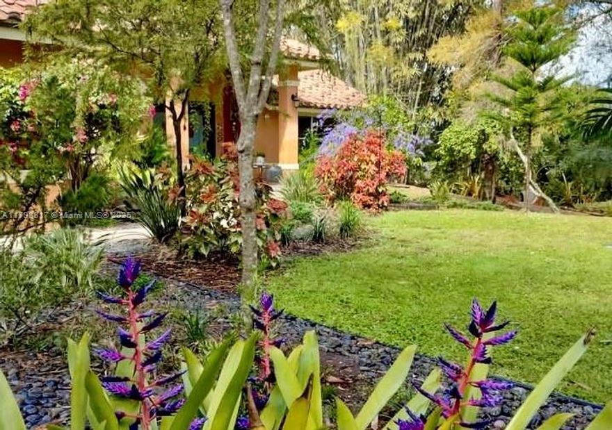 Own one of 49 exclusive custom homes in Westwoods — set on 1+ acre with tranquil lake views, surrounded by award-winning botanical gardens and rare tropical plants. As you enter this tropical estate, soaring cathedral ceilings flood the space with natural light. The open gourmet kitchen stuns with Maple Cabinetry, Labradorite countertops and backsplash. The floors provide a blend of natural elements: Brazilian Pecan in primary en-suite and guest room, Teak in bedrooms, and Bisque Saltillo throughout. Enjoy unmatched privacy, lake views, and low-key HOA, complete with dual-zone A/C, 2-car garage and workshop. Close to top-rated schools, hospitals, shopping, dining, and a short drive to PBI Airport, world-class beaches and Palm Beach Polo Club. Privacy. Prestige. Palm Beach at its finest.