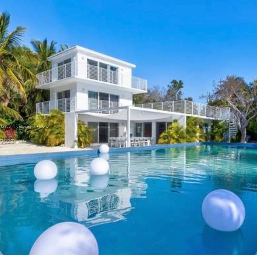 A Secluded Waterfront Paradise in the Heart of the Florida Keys. Step into a world of minimalistic elegance and tranquility at this one-of-a-kind coastal oasis. Tucked away on over an acre of lushly landscaped, private property stretching from highway to water, this architecturally unique home offers serene luxury and endless possibilities. Arrive via a tree-lined driveway to discover a striking three-story coastal retreat. Featuring four private en suite bedrooms, each with its separate entrance, the home is designed to provide privacy and relaxation for family and guests alike, great rental property for corporate retreat.