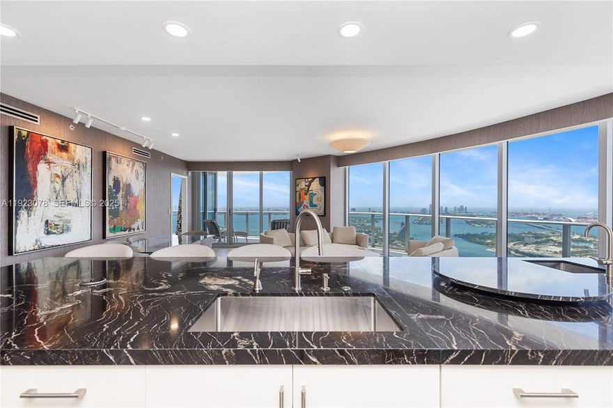 Completely upgraded with unobstructed panoramic views of Biscayne Bay, Miami Beach, Downtown Miami, and the Atlantic Ocean. This exceptional 3-bedroom + den, 4-bath residence features meticulously curated interiors and refined upgrades throughout. Tax Roll Interior: 2,018 Sq Ft (unit measures 2,365 Sq Ft per developer floor plan).

Every detail has been thoughtfully elevated beyond developer standards, showcasing luxury finishes that exude sophistication. No expense spared, no detail overlooked. The residence features a custom-designed kitchen (not developer-built) with a dedicated mini-bar area, Sub-Zero refrigerator, freezer drawers, and two Sub-Zero wine coolers, ideal for elevated entertaining and refined daily living.

Additional upgrades include Lualdi Italian doors by Piero Lissoni, wired-in electric window treatments, California Closets, and designer lighting throughout. The primary bathroom is a spa-like retreat with a custom vanity, Paris mirrors with integrated LED lighting, and TOTO Neorest toilets. Furnished to the highest level, featuring pieces by Roche Bobois, Minotti, Holly Hunt, and more.

Panoramic sunrise-to-sunset views create a seamless indoor-outdoor living experience, capturing the very best of Biscayne Bay, Brickell, Miami Beach, and the Miami skyline.