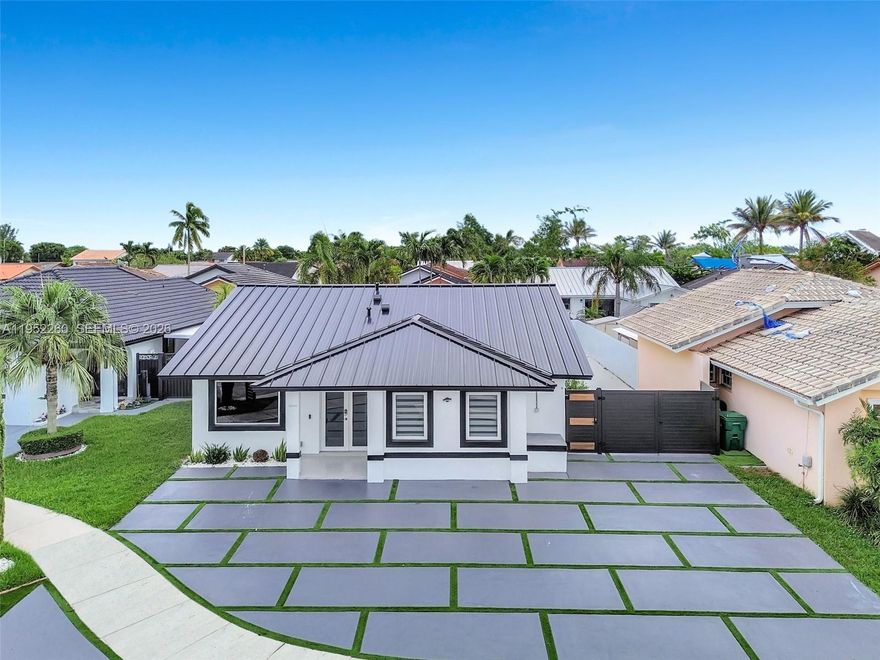 Experience luxury living in this beautifully renovated single-family residence where contemporary design meets everyday comfort. Tucked away on a quiet cul-de-sac, this modern home offers an open-concept layout with soaring 12-foot ceilings, creating bright, expansive living spaces filled with natural light. The home showcases premium finishes throughout, including high-end appliances, sleek custom cabinetry, and a striking Cristallo stone island with LED lighting. Elegant porcelain flooring flows seamlessly across the residence, complemented by thoughtfully designed bathrooms and spacious bedrooms featuring custom closets. A fully equipped second kitchen and additional family room enhance versatility and functionality, ideal for extended family, guests, or entertaining. Step outside to a private backyard retreat, perfect for hosting or relaxing in style. Additional highlights include a new metal roof, impact windows, and impact doors, providing enhanced security, efficiency, and peace of mind.