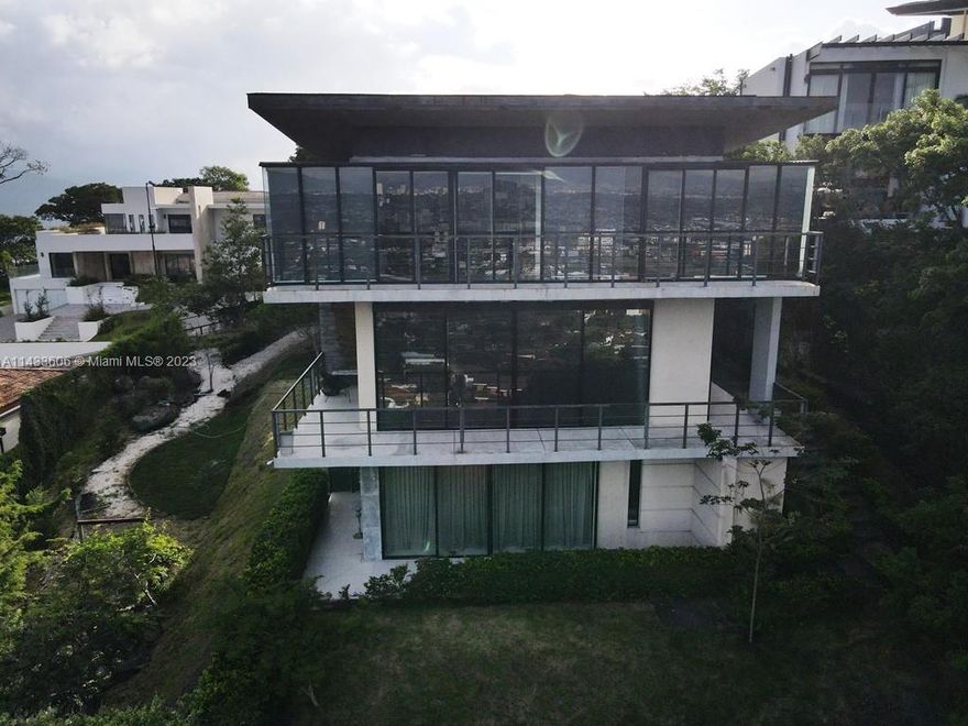 Stunning 3-story house in Cerro Real, Alto Las Palomas, Costa Rica.  Breathtaking panoramic views from every level.  Modern architecture harmonizes with natural surroundings.  3rd floor features 3 spacious bedrooms each w/ensuite bathrooms and open balcony including the primary bedroom and a large family room. 2nd floor entry level with open concept living & kitchen area along with maid's quarter.  Studio guesthouse on ground floor with private entrance. Outdoor courtyard between 3 car garage with grass roof top & the house with large U-shaped open balcony for enjoying the views and the breeze. Enjoy outdoor living with a lush Japanese style garden and walkway & saltwater pool. Gated community with top-notch security. Embrace luxury & tranquility in this exclusive hilltop Costa Rican gem.
