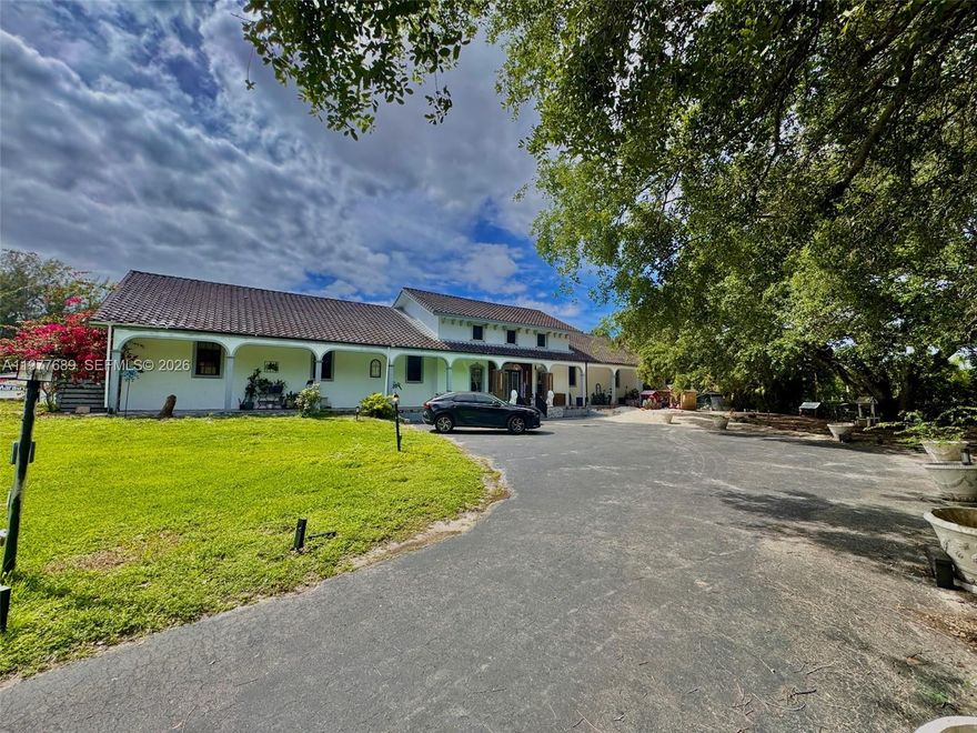 Set on over two landscaped acres in Southwest Ranches, this private estate offers space and privacy rarely found. Renovated in 2021, the residence is defined by 24-foot ceilings in the main living area, oversized 2’ x 4’ porcelain tile flooring, and a kitchen with custom cabinetry imported from Spain, quartz surfaces, stainless appliances, and a large island for everyday living and gatherings. The interior is anchored by an expansive primary suite designed as a private retreat, featuring a spa-style bath with floor-to-ceiling tile, freestanding tub, oversized shower, and office. A split floor plan provides privacy, with two bedrooms on one wing and three on the other, including an additional en-suite bedroom. Above the main living area, a loft-style upper level with vaulted wood ceilings serves as a lounge with wet bar and balcony. Outdoor spaces are designed to be lived in, offering a covered terrace, travertine pool deck, resort-style pool and spa, poolside bar, and a vine-covered pergola walkway. Beyond the main residence, the property includes a 1,260 SF air-conditioned garage/workshop with water and electric, offering space for multiple vehicles and potential for lifts or hobby use. Fully fenced with two motorized gates, RV access with hookups, agricultural zoning, and space for horses. Ideally located near Weston, this estate offers access to top-rated schools, shopping and dining while maintaining the privacy, space, and character that define Southwest Ranches living.