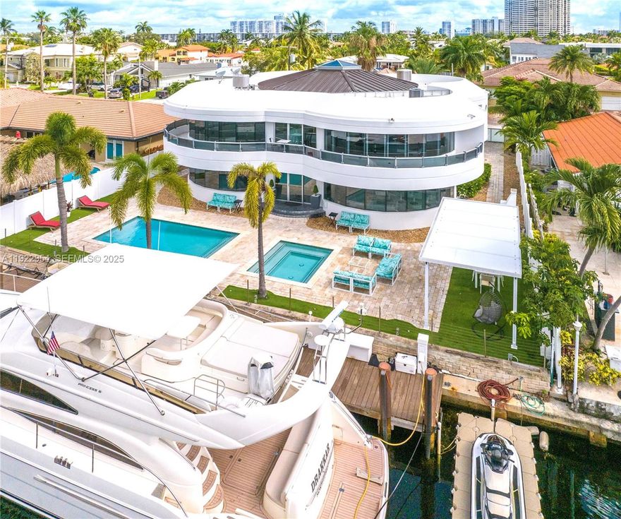 Best-Priced Modern Waterfront Residence in All of Miami Beach. A striking all-white concrete masterpiece with bold Iron Man / Tony Stark–inspired architecture, offering 80 feet of premier water frontage just a short walk to the beach. Located in the exclusive, guard-gated Eastern Shores community of Sunny Isles. This ultra-modern waterfront estate features a rare full concrete perimeter wall, private electric gate, dramatic 20-ft ceilings, and a stunning vaulted skylight that floods the home with natural light. Elegant design details include curved architectural staircases, wraparound terraces, and 36x36 white porcelain flooring throughout.The residence offers 6 bedrooms and 6.5 ensuite baths, including a luxurious primary suite with its own private terrace, jet spa tub, and dual walk-in closets. A fully integrated $180k Crestron Smart Home system, controlled by 3 iPads and smartphone-enabled, seamlessly manages intelligent color-changing lighting, 28 built-in speakers, climate, security, and more.
Outdoor living is elevated with a waterfront pool and hot tub, outdoor brick oven, covered entertainment patio with ceiling fan, and a 2-car supercar garage. Perfectly situated minutes from the beach, shopping, dining, Aventura, Bal Harbour, Miami International Airport, and South Beach. A modern fortress of design and technology—unmatched at this price point