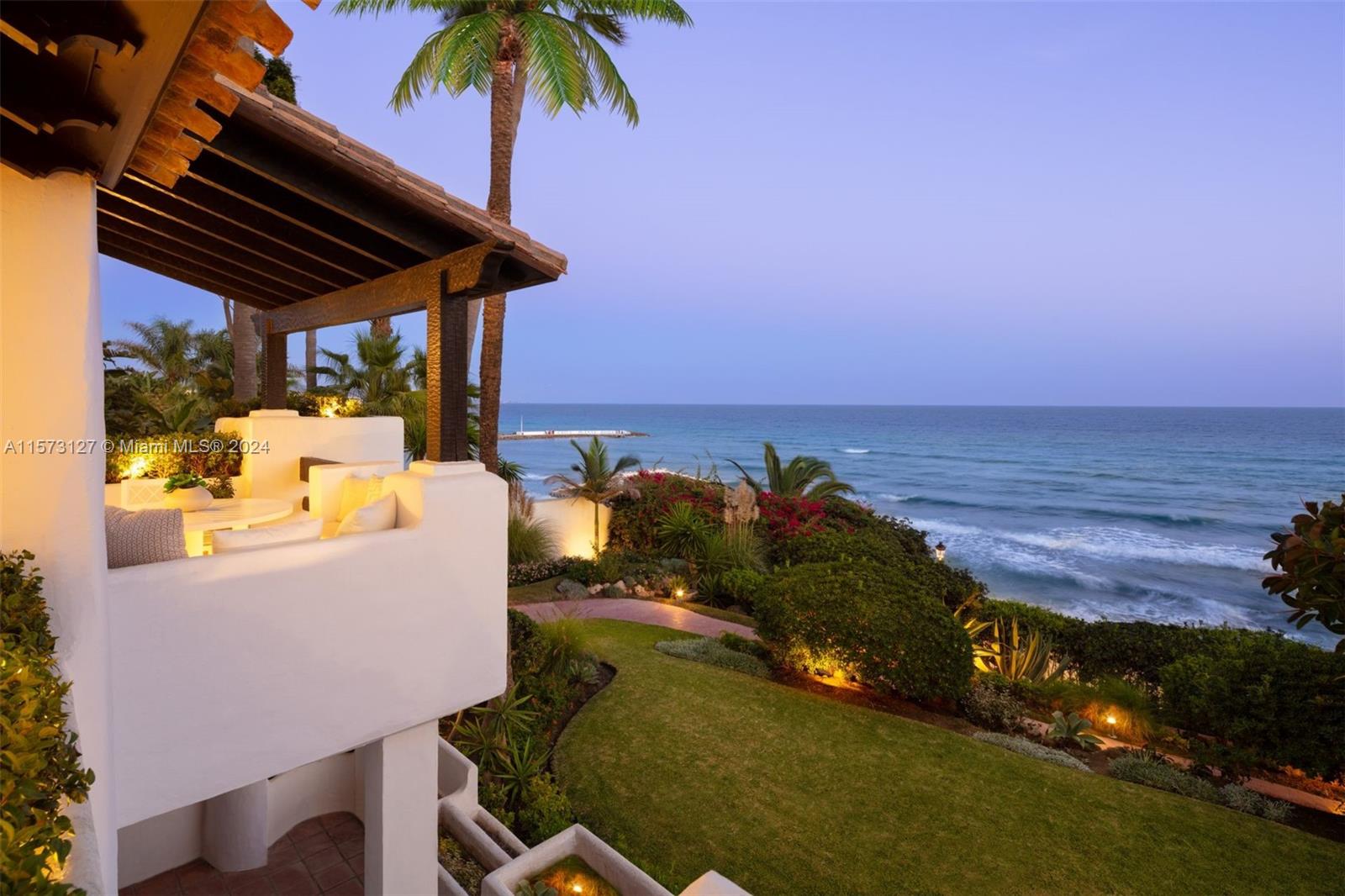 Property is located in Marbella, Spain. Coconut, a luxurious duplex in Puente Romano Resort, boasts stunning sea views and southern exposure. It features expansive terraces, direct terrace access via sliding doors, and a serene blue and neutral color palette. The living area includes a bookshelf, bar, and fireplace, connected to a dining area and a kitchen with a marble island and modern appliances. Two ground floor guest bedrooms have en-suite bathrooms. The master suite upstairs offers a private living area with a fireplace, walk-in closet, en-suite bathroom, and a terrace with a pool overlooking the sea, encapsulating Marbella's elite beachside lifestyle.