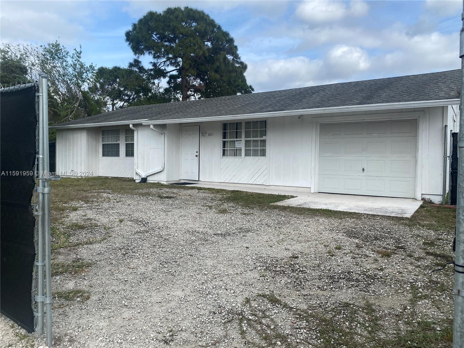 The property features a 3-bedroom, 2-bathroom house repurposed as office space, situated on two 0.23-acre general commercial lots. A tall chain-link fence encloses almost the entire property. It includes two double-gated entrances: one at the front of the building and another at the southern boundary sizable enough to accommodate RVs, boats, and semi-trucks. Around three-quarters of the property is surfaced with asphalt millings. A new A/C unit was installed early 2022.