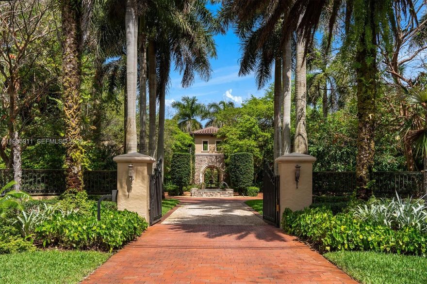 Set on a sprawling 1.12-acre lot in the heart of Pinecrest, this extraordinary grand Tuscan-inspired estate offers 6,624 SF under air and 9,771 total SF with 6 bedrooms and 8.5 bathrooms. A gated entry and sweeping oak-lined driveway lead to a private, resort-style compound defined by timeless Mediterranean architecture, a barrel tile roof, and lush, manicured grounds. The multi-structure layout surrounds a spectacular heated saltwater pool and spa, with covered terraces and a fully equipped summer kitchen for seamless indoor-outdoor living. Interiors feature soaring ceilings, travertine, wood and stone floors, a dramatic atrium courtyard, formal living and dining rooms, and a spacious family room. The chef’s kitchen is equipped with granite countertops, custom cabinetry, Sub-Zero refrigeration, and a full Thermador appliance suite. Additional highlights include a custom bar, wine cellar, home theater, and private office. The main-level primary suite offers a sitting area and a spa-inspired bath with soaking tub, dual vanities, and walk-in closets. A separate guest residence with living area and kitchenette, plus staff quarters, provide flexibility. Modern comforts include impact windows, Control4 smart home and audio, Generac generator, mosquito system, 3-car garage, and more—delivering exceptional privacy and comfort in one of Pinecrest’s most desirable settings.