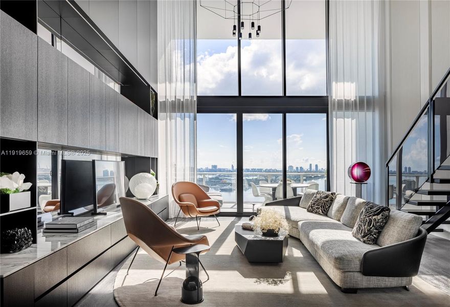 A fusion of architecture and high design, this sophisticated loft-style residence sits 22 stories high in the iconic Ten Museum Park tower by visionary architect Chad Oppenheim. Designed by award-winning B&G Design, the 1,802 SF home showcases dramatic 20-ft floor-to-ceiling impact glass that floods the 2-bedroom, 2.5-bath layout with natural light and breathtaking views. The minimalist interiors feature a streamlined aesthetic, a striking smoked-glass and steel staircase, and sculptural vertical millwork—high-impact elements rarely seen at this level. Panoramic east-facing views stretch over Museum Park, Biscayne Bay, and the Miami and South Beach skyline. The sleek kitchen features custom Italian cabinetry plus an oversized natural stone island as a striking focal point. Elegantly grained flooring, imported marble surfaces, and built-in cabinetry elevate the residence. Additional features include motorized solar shades, a full-size Miele washer/dryer, two assigned parking spaces, and air-conditioned storage. Exclusive Five-Star Wellness Amenities at Ten Museum Park sets the global standard for resort living, offering residents an unparalleled wellness experience powered by the world-renowned Clinique La Prairie Spa of Montreux, Switzerland.