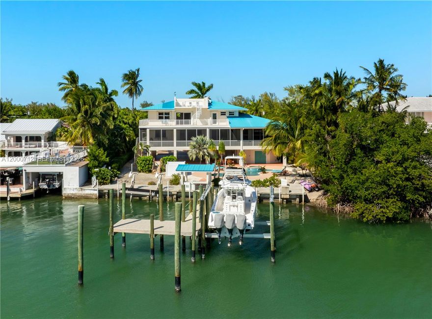 Big, beautiful, and exceptionally solid, this waterfront Islamorada residence is perfectly situated on Sandy Cove Basin with protected deep-water dockage for multiple boats and direct bay access. A gated, pavered double driveway leads to an inviting foyer where marble floors and a private elevator welcome you. The elevated living level features a spacious great room with fireplace and coral accents, ideal for entertaining, along with a chef's kitchen offering custom teak cabinetry, granite countertops, island cooktop, and premium Sub-Zero and Bosch appliances. Wide screened porches extend the living space and capture open waterfront views. The home offers 5 bedrooms and 5.5 baths, a resort-style pool, and excellent updates including a new dock, new boat lift, and new A/C systems. A privacy wall enhances the secluded feel of this quiet, one-street neighborhood known for its consistently lovely homes. An exceptional opportunity for refined island living with outstanding boating access.