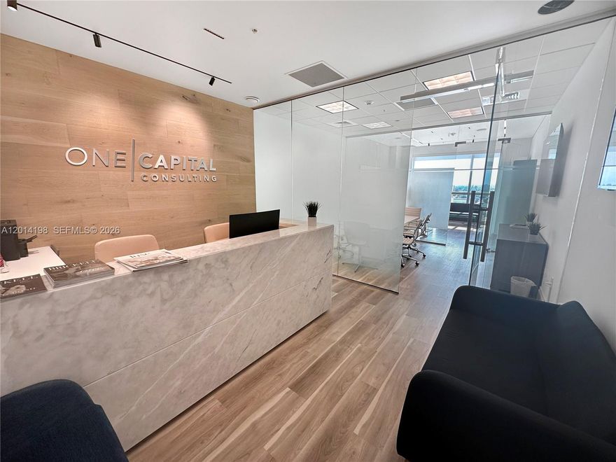 Fully furnished office space at Latitude, ideal for a professional business setup. The layout is thoughtfully divided into three functional areas. The entrance area features a large marble desk, printer, and TV, providing a complete and efficient workspace for daily operations. A spacious meeting room accommodates up to eight people and includes a presentation TV, perfect for conferences and client presentations. The private office showcases beautiful sunset views, electric shades, and a board for planning and organization. Elegant flooring and sleek glass partitions enhance the modern design, creating a polished and productive work environment. Move-in ready.