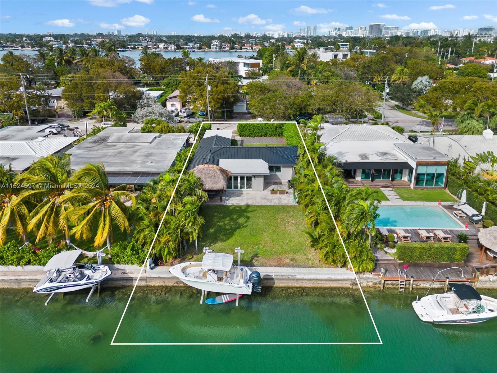 Charming and renovated waterfront home in Biscayne Point boasts 3 bedrooms and 2 baths. Featuring original terrazzo floors, hurricane windows and doors, as well as a 10,000-pound boat lift. This residence is thoughtfully updated with new bathrooms and a modern eat-in kitchen with stainless steel appliances. 1-car garage with potential to convert into a fourth bedroom or third bath plus ample space for a pool. Indulge in a candlelit dinner or a morning breakfast beneath the tiki hut, overlooking the canal, where the lush landscaping adds to the tranquil ambiance. Situated on man-made islands in Biscayne Bay, Biscayne Point offers a mix of renovated mid-century homes & modern luxury residences. Enjoy the allure of waterfront living, making this a sought-after destination in the Miami Beach.