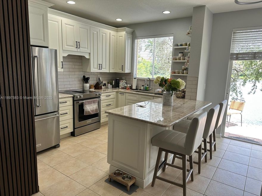 Fully renovated 2 bed, 2.5 bath lake-view townhouse featuring a modern open-concept design with a gourmet white kitchen with marble countertops, tile floors, and a chic wood-slat accent wall. Enjoy premium upgrades: whole-house water filtration system, hurricane impact windows/doors, stylish Zebra blinds, and new Samsung washer and dryer. Both baths are custom-remodeled, including a glass walk-in shower with pebble floor. This home offers high-end style and ultimate protection.