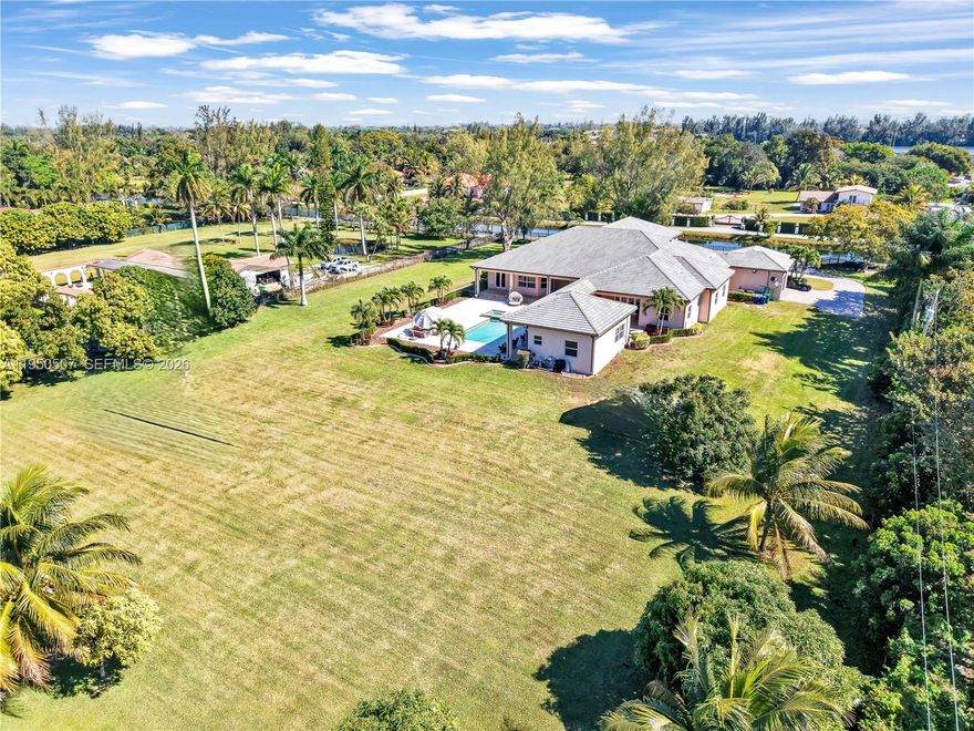 Resort-style living in the heart of Miramar, located in prestigious Country Club Ranches with no HOA. Situated on 2.5 acres, this custom-built 2017 estate offers a 6BD/5BA/2HB main home plus a private 1BD/1BA guest house with full kitchen and living area. Features include a 3-car garage with ample storage, expansive primary suite with private gym, oversized walk-in closets, and spa-like bath with soaking tub, large shower, double vanities, and bidet. Gourmet kitchen with 3 ovens and top-of-the-line appliances. Custom laundry room with built-in ironing board. Fully energy efficient with impact windows and doors and a 500-gallon generator powering the entire home up to 14 days. Backyard oasis includes gas-heated saltwater pool and jacuzzi with ample space for RV parking, horses, or agricultural use.