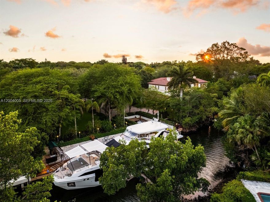 Situated in the exclusive gated community of Cocoplum Phase 1, with 24-hour Coral Gables police protection and resident tennis courts, this Italian villa-inspired waterfront estate by architect Ramon Pacheco offers 8,695 total SF on nearly one Acre lot, with 6 bedrooms, 7 full and 1 half baths. Built on pilings with high elevation, this immaculate single-owner gem showcases ~14-ft ceilings, grand proportions, elevator-ready design, four A/C units, A/C-equipped garage, and a Sony integrated audio system. A striking Mediterranean façade with triple-arched portico, classical columns, and an ornate iron-and-glass entry sets the tone. Lush grounds with 28 mature oak hammocks frame a circular driveway and expansive outdoor living. Enjoy direct ocean access with no bridges to Biscayne Bay, featuring a 100-ft seawall, additional 70-ft dock, and grandfathered 40-ft slip. The keystone marina deck, pool with waterfall spa, cabana, covered terraces, and summer kitchen create a resort-style setting. Interiors feature a dramatic triple-height foyer, marble staircase, refined millwork, and marble and wood floors. The gourmet kitchen offers custom Italian cabinetry, quartz counters, premium appliances, and wine storage. The expansive primary suite offers a private office, vaulted ceilings, and a spa-inspired bath with bespoke finishes and custom walk-in closets—delivering a refined private retreat within this exceptional waterfront residence.