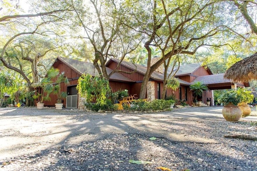 Discover the potential of this exceptional property located in the peaceful and fast-growing Redland area of South Miami-Dade. Set among mature greenery and wide-open spaces, this rare blend of privacy, space, and opportunity—perfect for buyers seeking room to grow, invest, or create their ideal lifestyle.
This extraordinary estate offers 4–5 acres of private, fully usable land with unmatched versatility. The main residence features 5 bedrooms & 3 bathrooms, built with solid concrete block construction accented by red cedar, impact windows & doors, and a warm, inviting fireplace. A tucked away 1/1 guest house for extended family or guests, and a dedicated office house, ideal for work. Designed for entertaining, enjoy expansive outdoor living spaces, a full exterior kitchen, BBQ, and multiple tiki huts with designated entertainment areas ideal for gatherings, events or meditation. Equestrian and agricultural amenities include horse stables, animal barns, and a private aviary, perfect for bird enthusiasts or specialty use. The open acreage supports livestock, farming, or recreational pursuits, all while offering privacy and serene country living with convenient access to major roads and amenities. Minutes away from the Florida Keys.