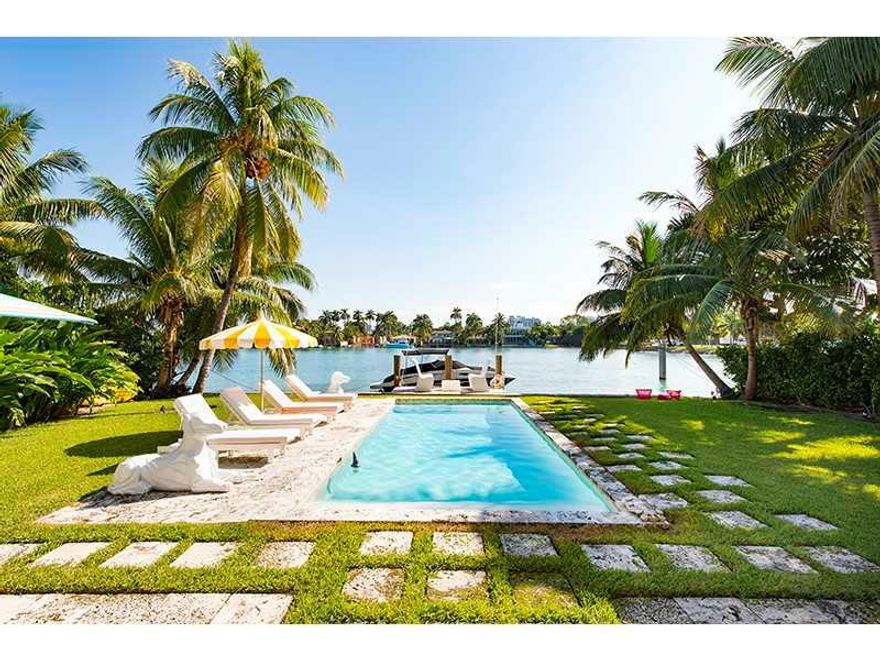 Artfully restored 2-story charming Floridian style waterfront home on Venetian Islands. Architectural features included curved staircase, high ceilings, and quaint fireplace which preside over modern touches - S/S appliances, eat-in kitchen, impact glass,  custom hurricane shutter. Open formal dining & living rooms, spacious master suite with private balcony, family room, library, downstairs staff suite, plus a large mature garden, grass-decked pool & dock are picture perfect. Oversize 14,000 sq foot lot.